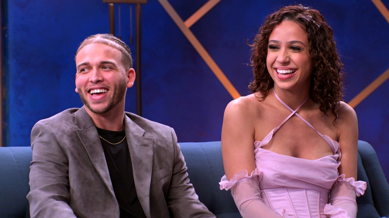 Jake Cunningham and Rae Williams sit together smiling on a couch for 'The Ultimatum' reunion.