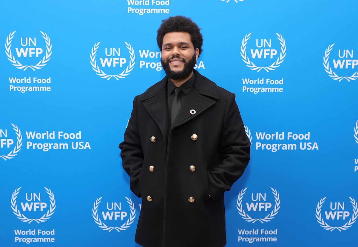 Star of HBO's 'The Idol' The Weeknd wearing a long black coat and smiling on the red carpet
