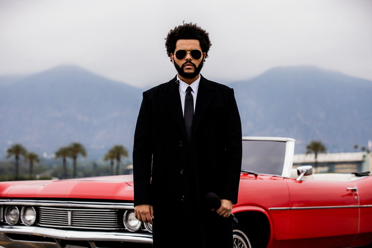 The Weeknd poses in front of a red convertible during a performance at the 2021 Billboard Music Awards in LA.