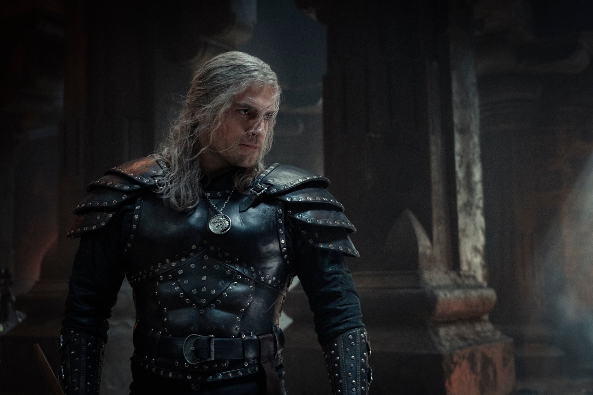 Henry Cavill as Geralt of Rivia in 'The Witcher' Season 2. He's wearing black armor and looks ready to fight.