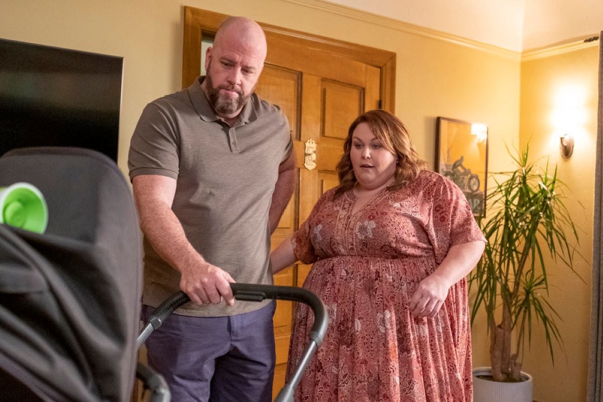 'This Is Us' Season 6 Episode 12, which airs tonight, stars Chris Sullivan and Chrissy Metz, in character as Toby and Kate, share a scene. Toby wears a gray polo shirt and blue pants. Kate wears a pink floral dress.