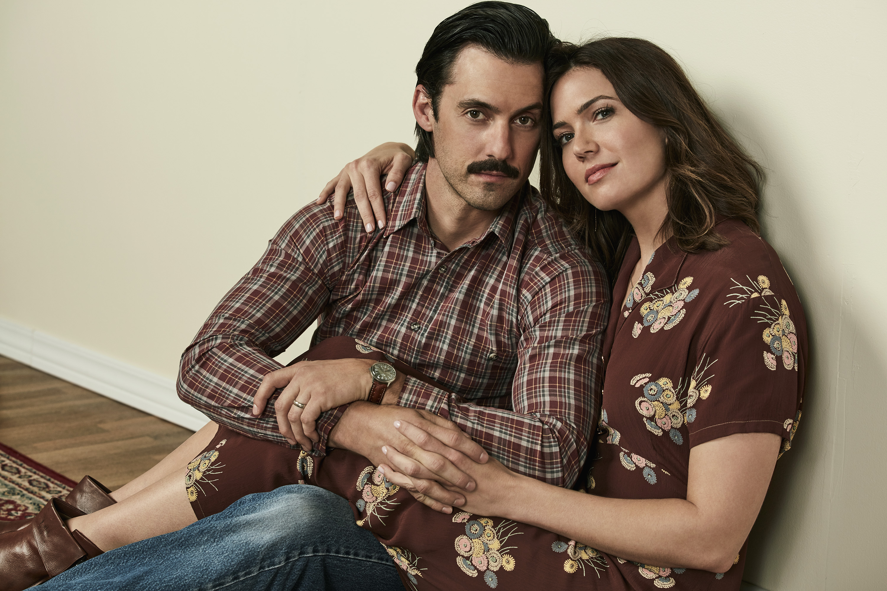 This Is Us Season 6 actors Milo Ventimiglia and Mandy Moore pose while sitting on the floor next to each other.
