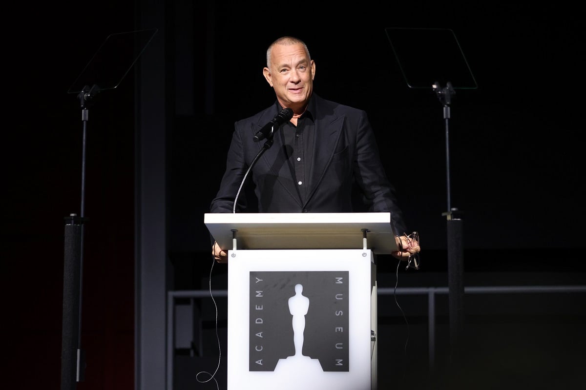 Tom Hanks smiles while speaking on stage.