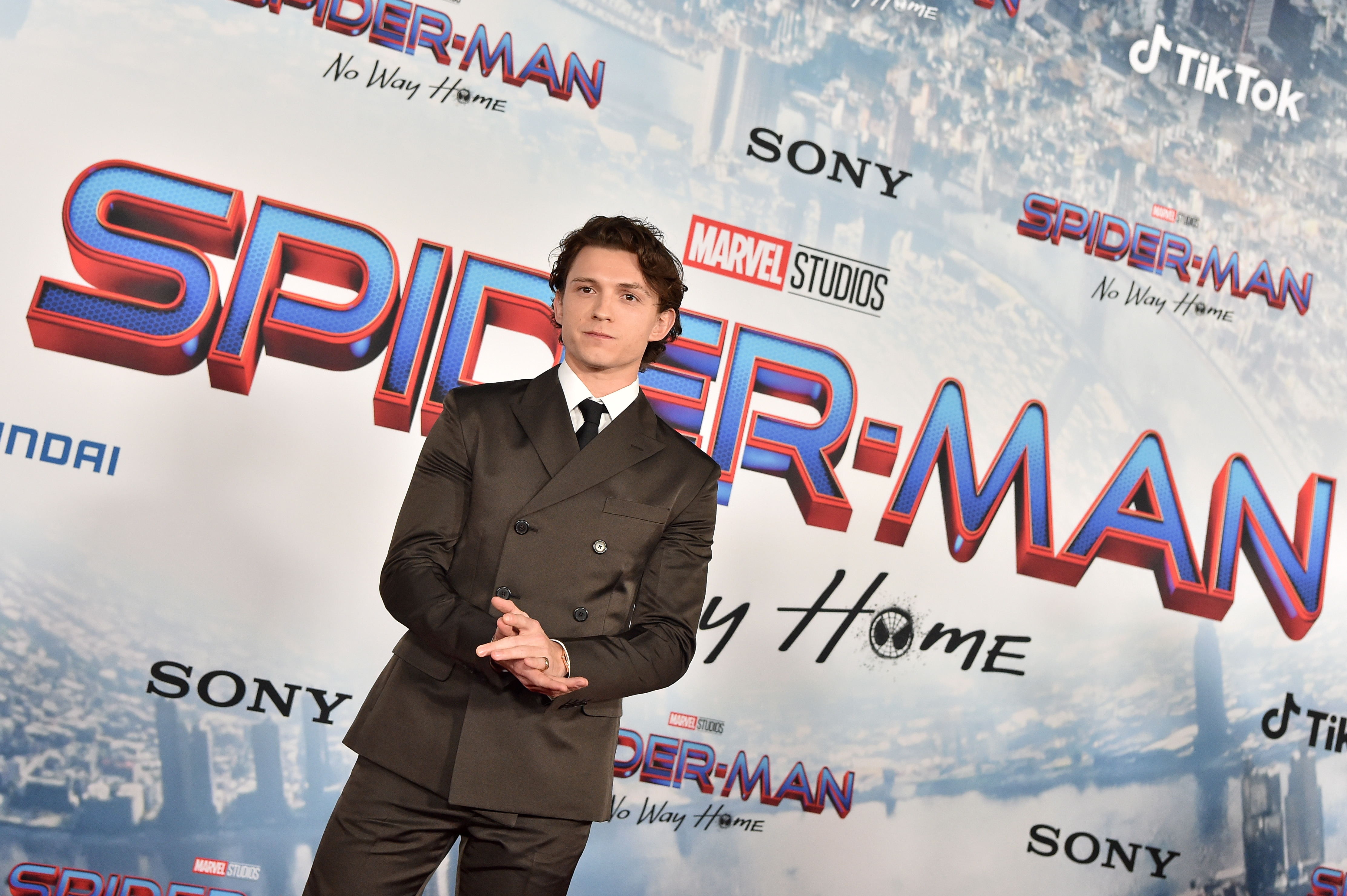 'Spider-Man: No Way Home,' which contains multiple Easter eggs, star Tom Holland wears a dark gray suit over a white button-up shirt and black tie.