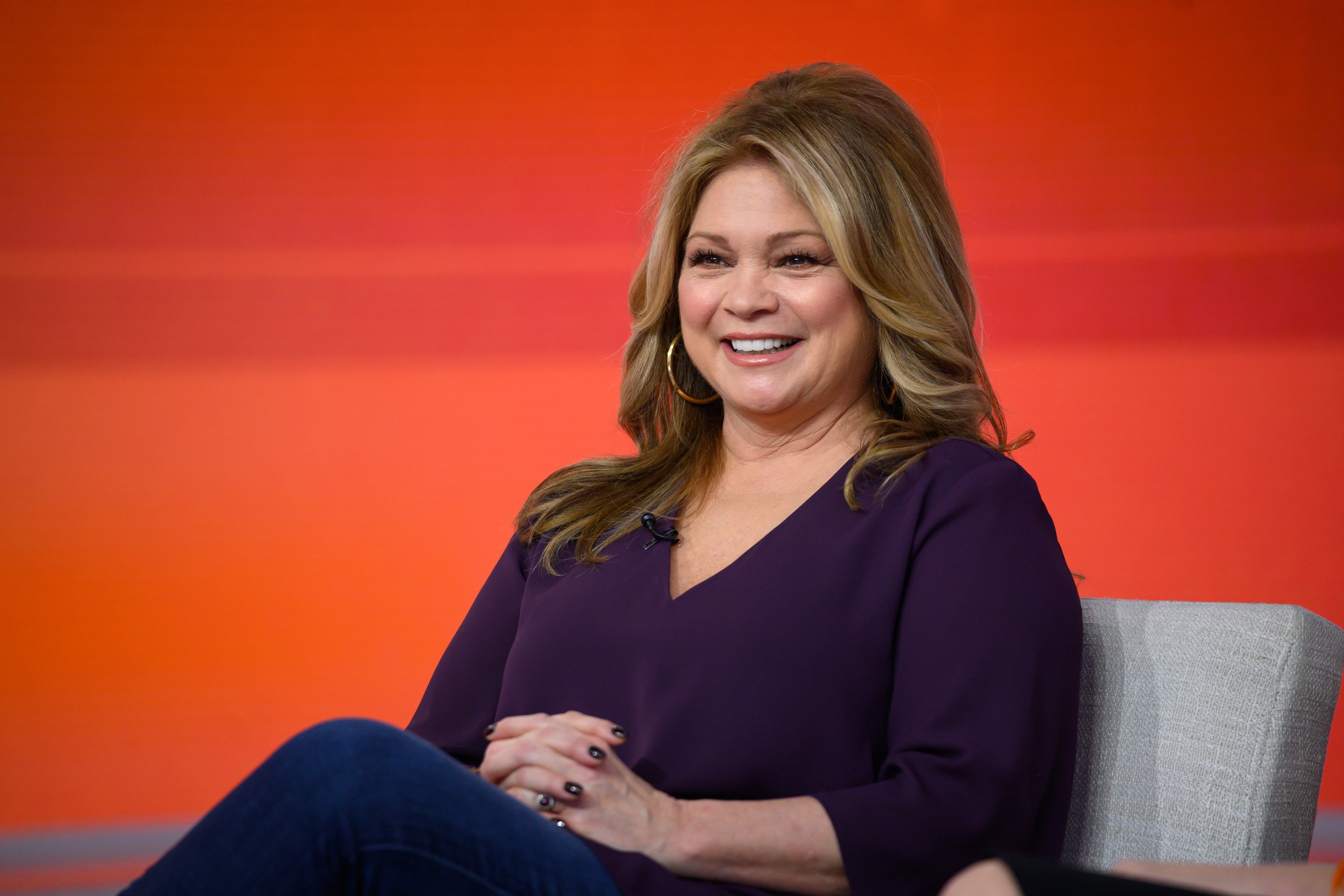 Food Network personality Valerie Bertinelli wears a long-sleeved, v-necked purple sweater in this photograph.