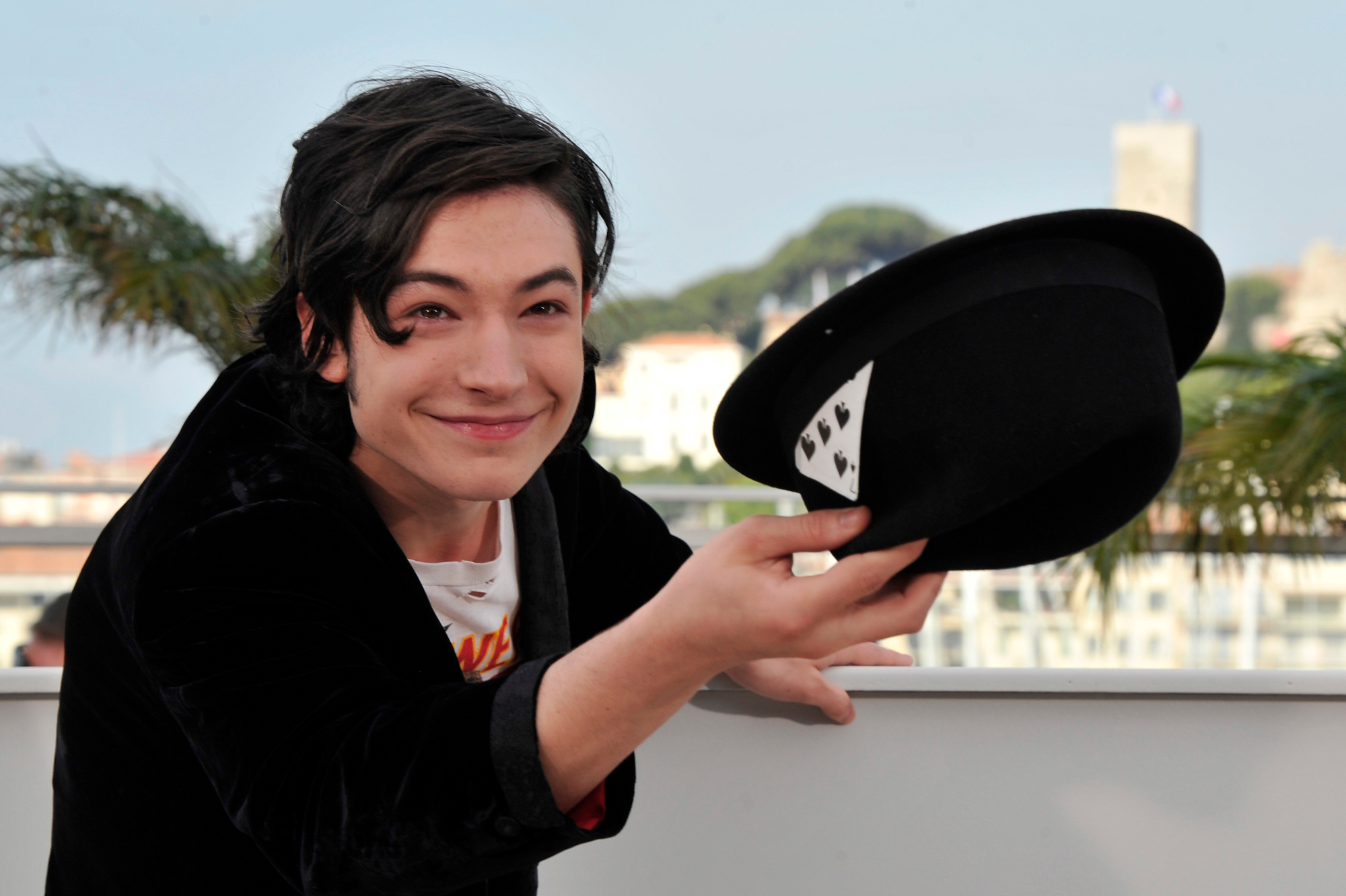 'We Need to Talk About Kevin' star Ezra Miller smiling and holding his hat out toward cameras at the 64th Cannes International Film Festival