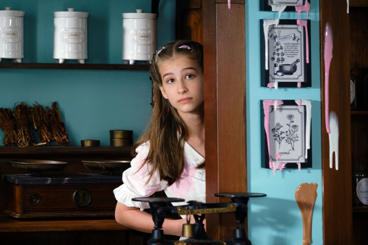 Alllie (Jaeda Lily Miller) peeks out from behind a wall in 'When Calls the Heart' Season 9 Episode 6