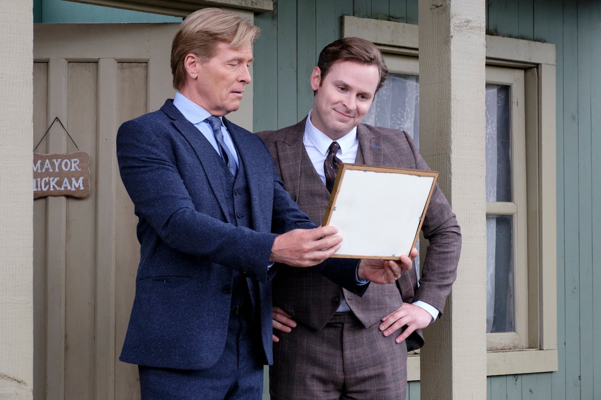 Bill (Jack Wagner), holding a framed photo, standing next to Mike Hickam (Ben Rosenbaum) in 'When Calls the Heart' Season 9 Episode 6