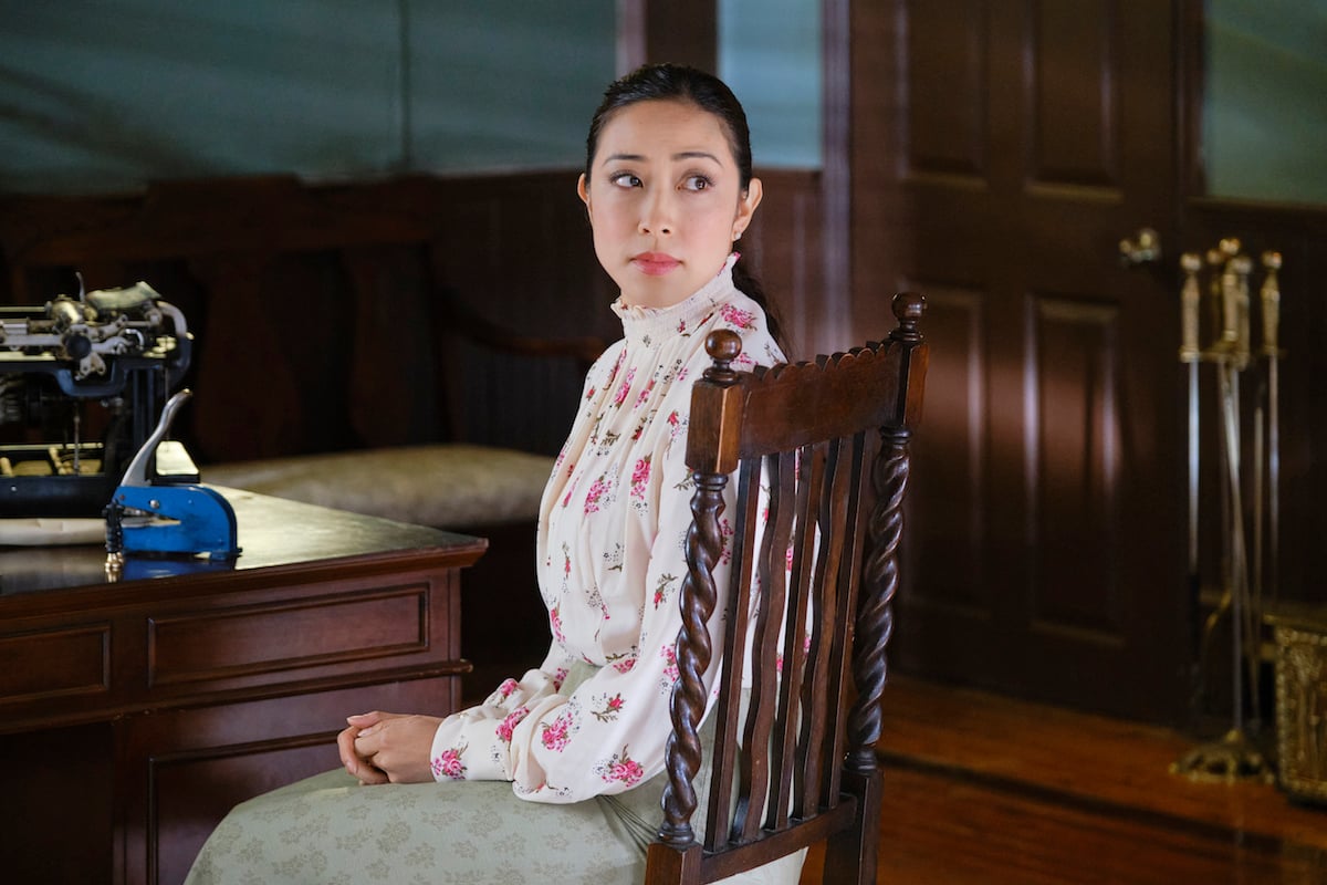 Amanda Wong as Mei Sou, sitting in a chair and looking over her shoulder in 'When Calls the Heart' Season 9 Episode 7