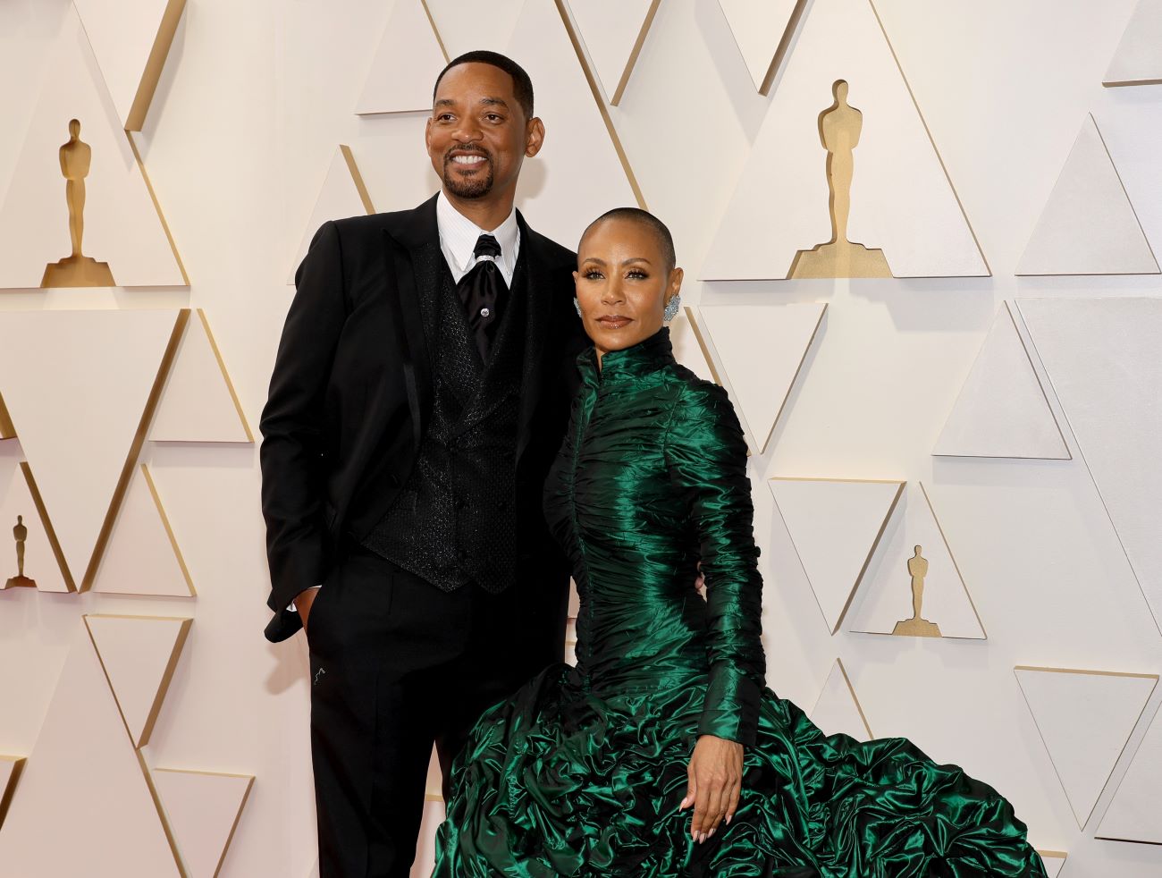 Will Smith wears a suit and Jada Pinkett Smith wears a green dress on the Oscars red carpet.