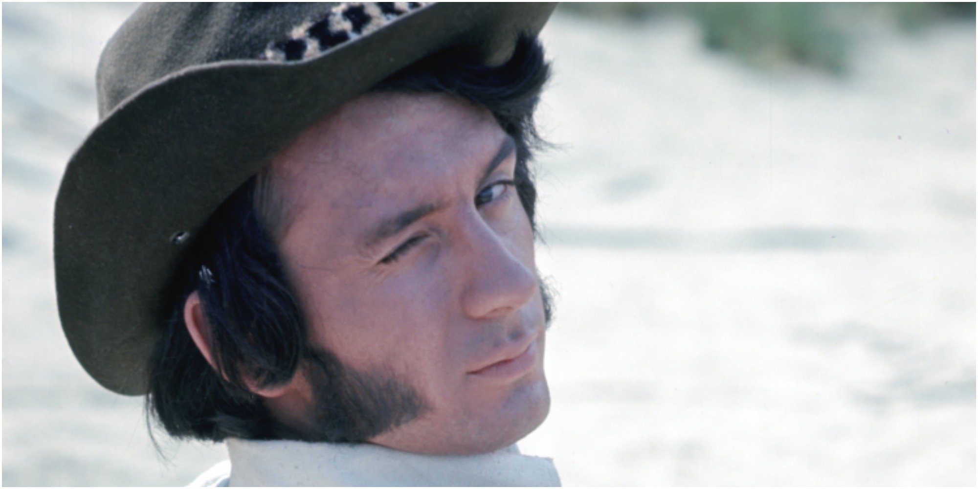Mike Nesmith wears a cowboy hat and winks on the set of The Monkees.