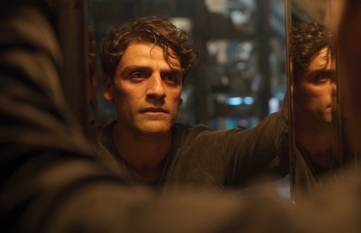 Oscar Isaac as Steven Grant/Marc Spector, looking at himself in a mirror in Moon Knight