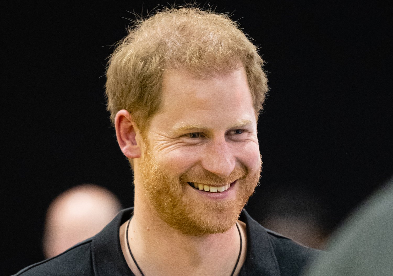 Prince Harry smiles while wearing a black shirt at the Invictus Games