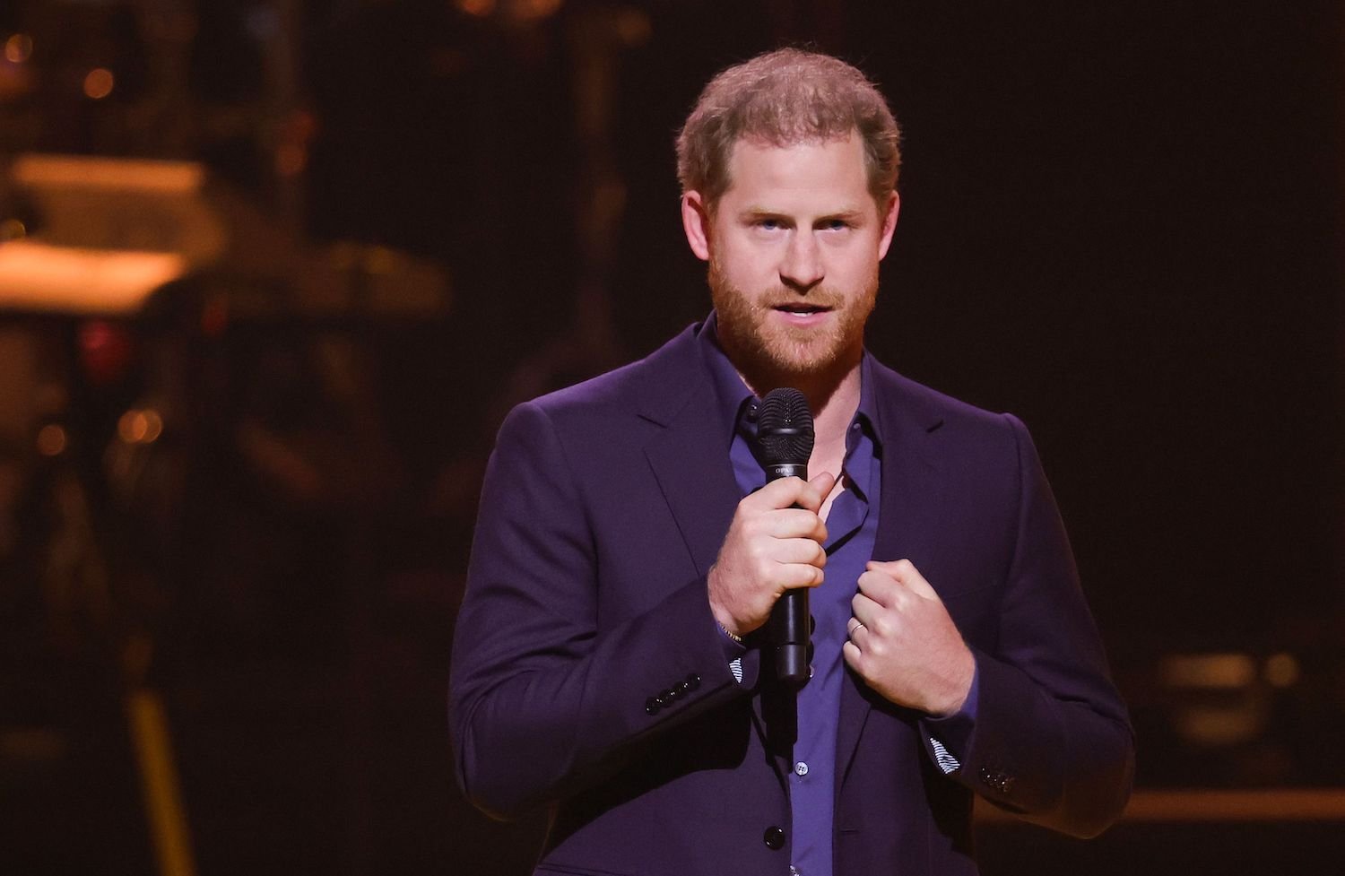 Prince Harry wears a suit and holds a microphone while addressing the audience at the 2022 Invictus Games closing ceremony