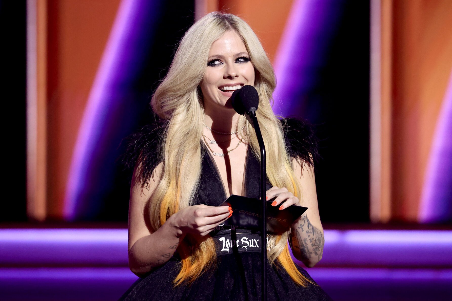 Avril Lavigne, who's seldom on TikTok, stands on stage speaking into a mic.