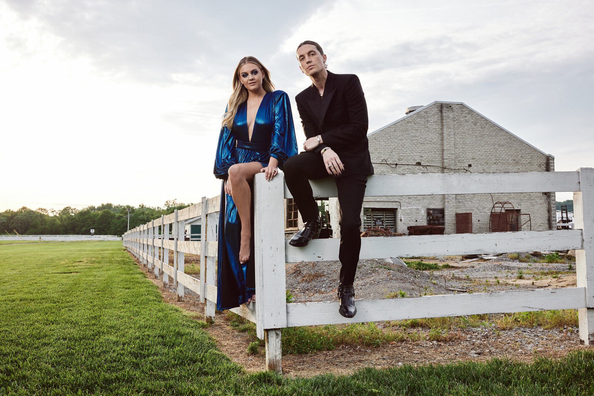 Kelsea Ballerini and Paul Klein of 'I Quit Drinking' sit on a white fence.