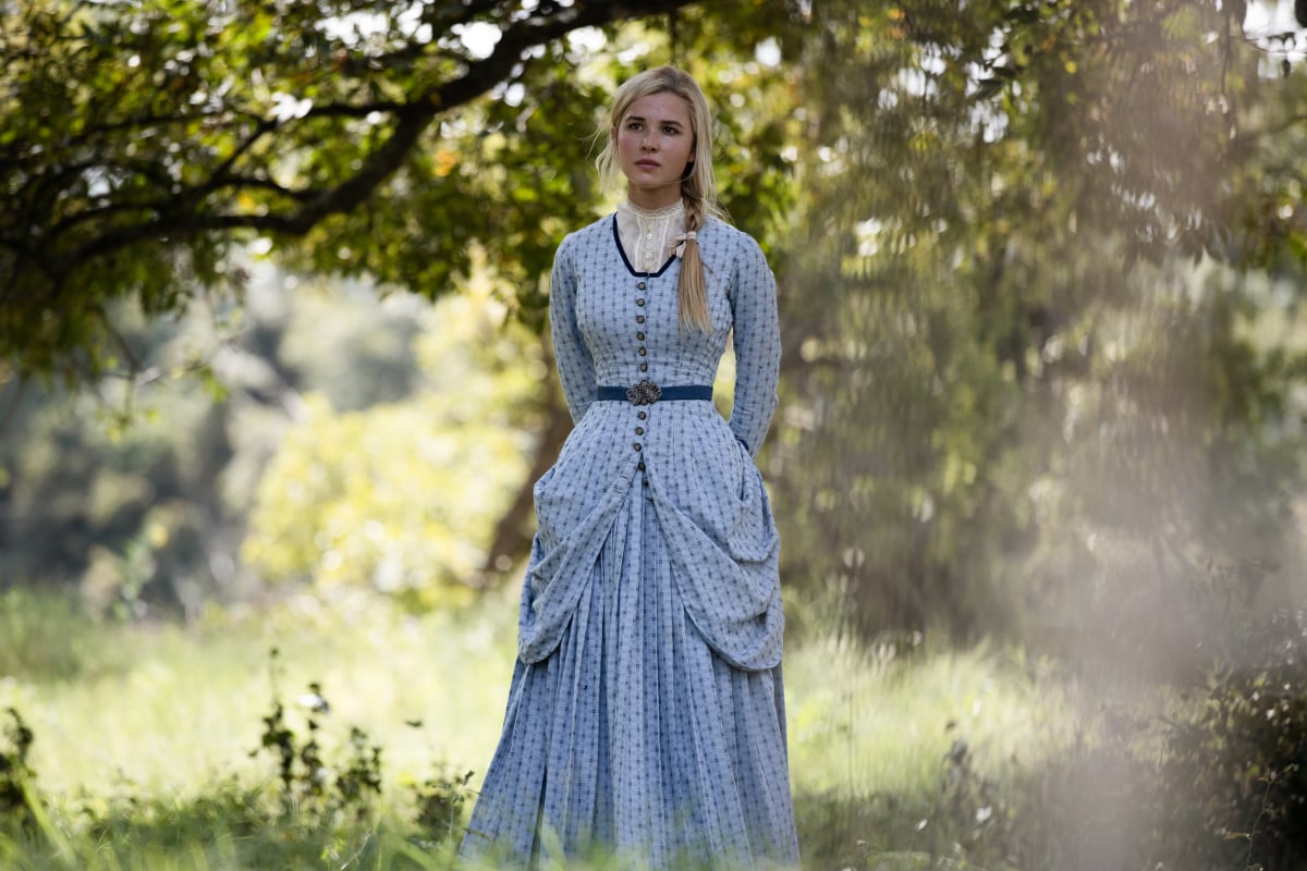 '1883': Isabel May stands under a tree in a blue dress, in a role Taylor Sheridan promised her