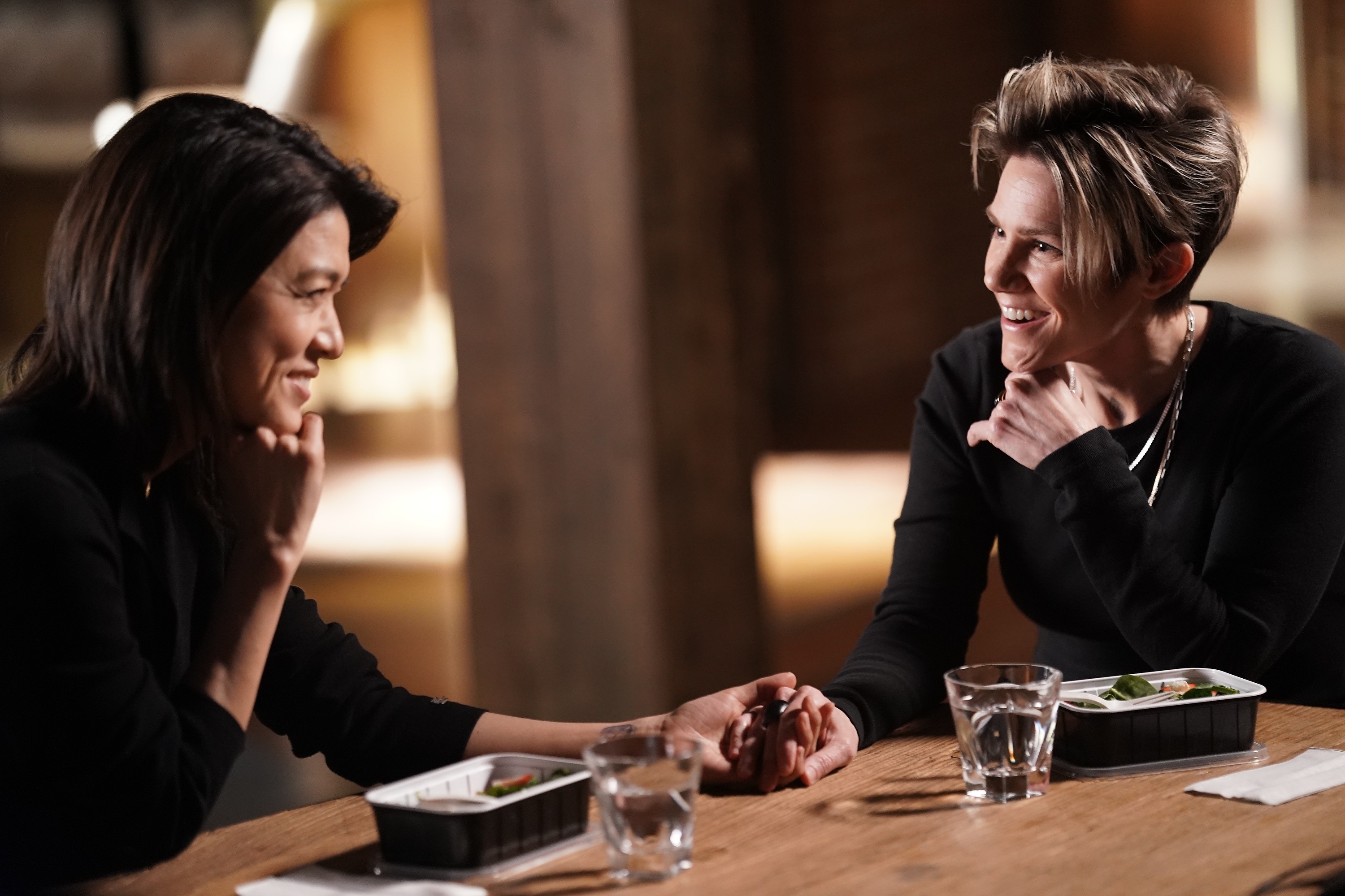 'A Million Little Things' cast members Grace Park and Cameron Esposito sitting together eating and talking