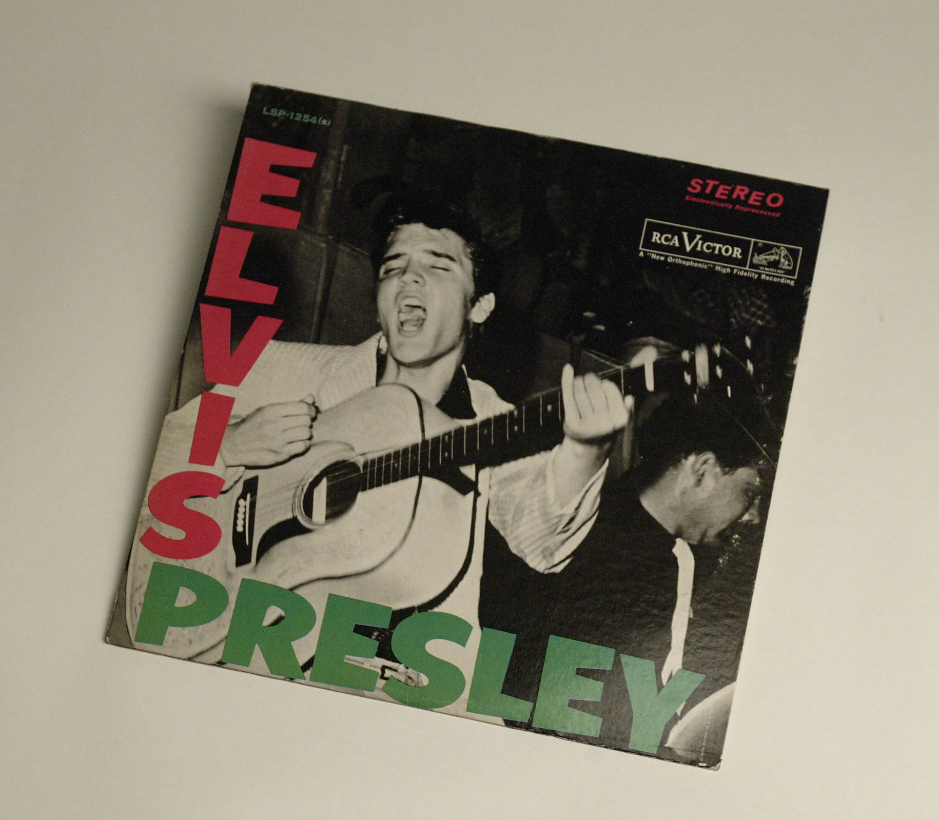 Elvis Presley singing a song on the cover of his first album