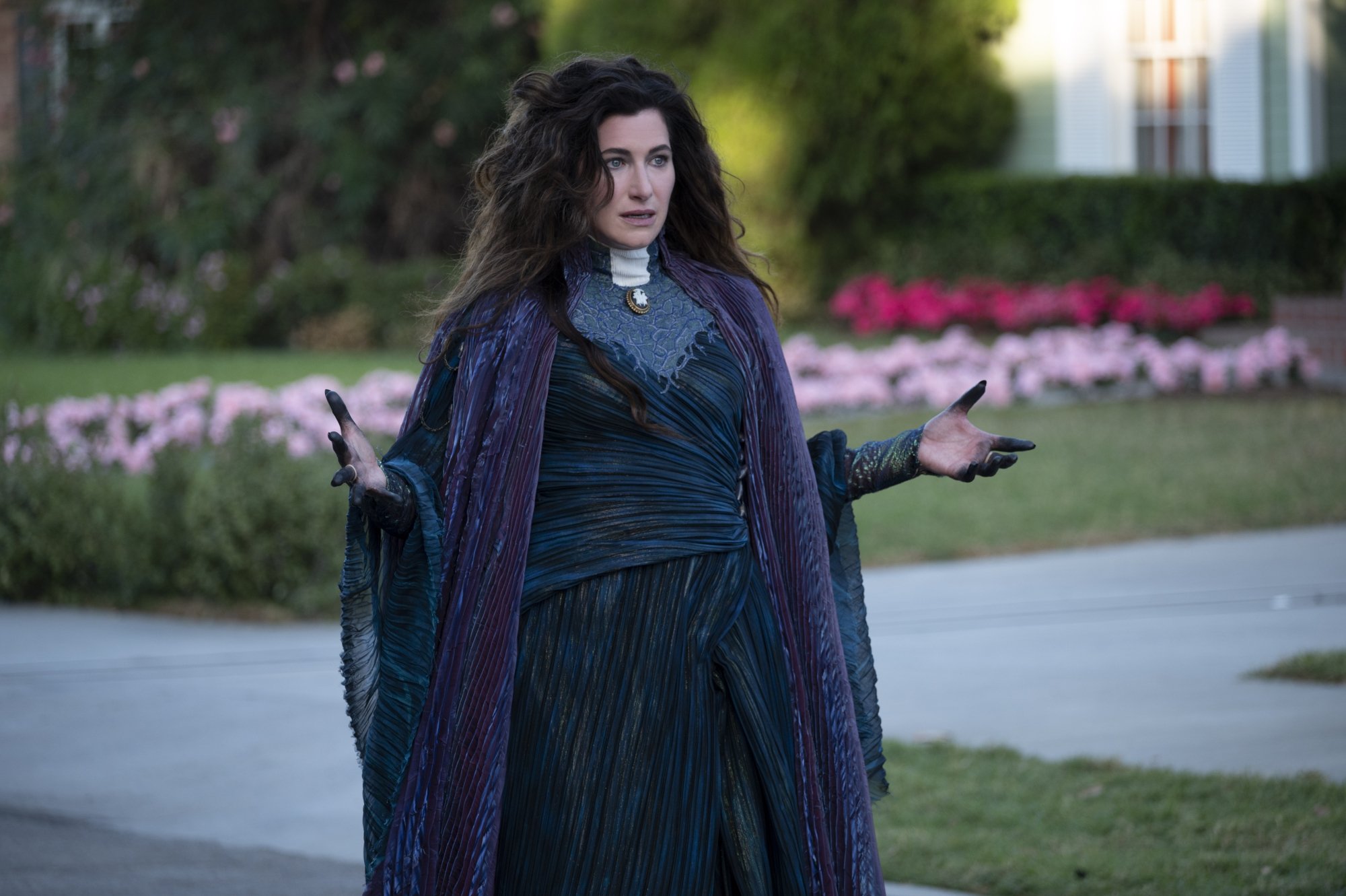 Kathryn Hahn as Agatha Harkness, whose storyline may be impacted by the ending of 'Doctor Strange 2,' in the 'WandaVision' finale. She's wearing a dark green dress and purple cloak, and her hair is curly and down.