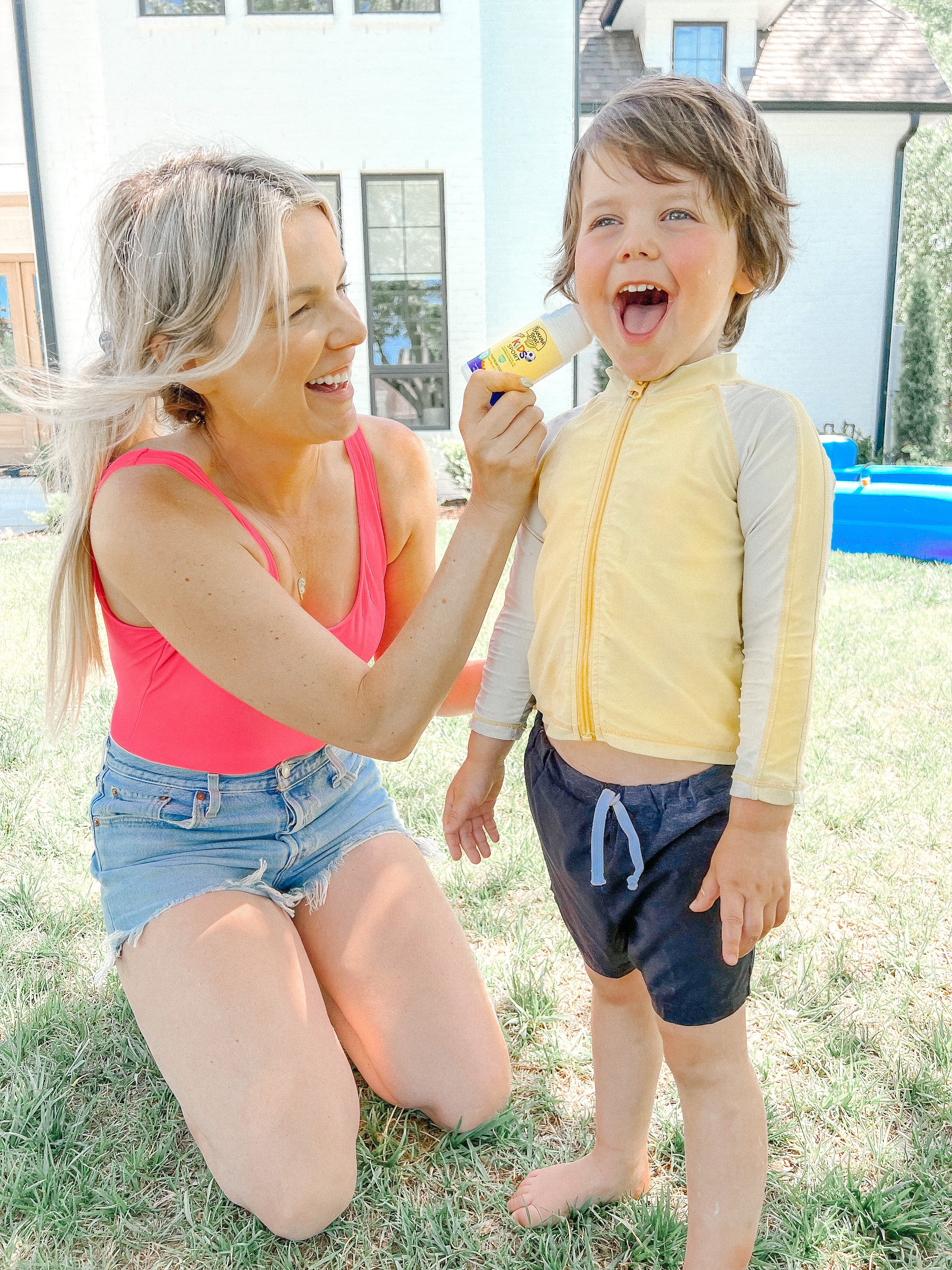 Former 'Bachelorette' Ali Fedotowsky wearing a tank top and jean shorts while putting Banana Boat sunscreen on her son.