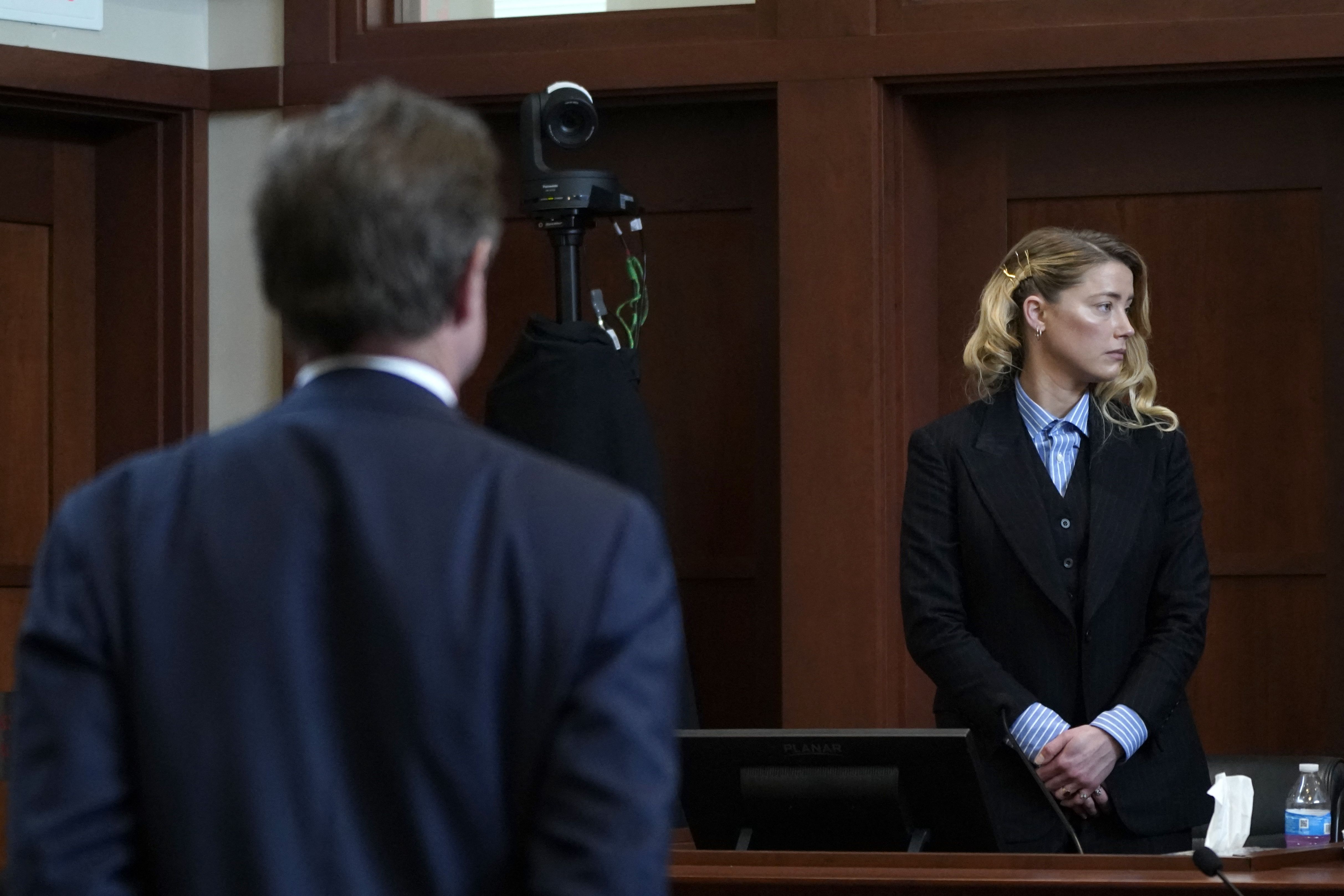 ctor Amber Heard stands up for recess as Ben Chew, attorney for actor Johnny Depp, looks on at Fairfax County Circuit Court during a defamation case against her by Depp in Fairfax, Virginia, on May 4, 2022. - US actor Johnny Depp sued his ex-wife Amber Heard for libel in Fairfax County Circuit Court after she wrote an op-ed piece in The Washington Post in 2018 referring to herself as a "public figure representing domestic abuse."