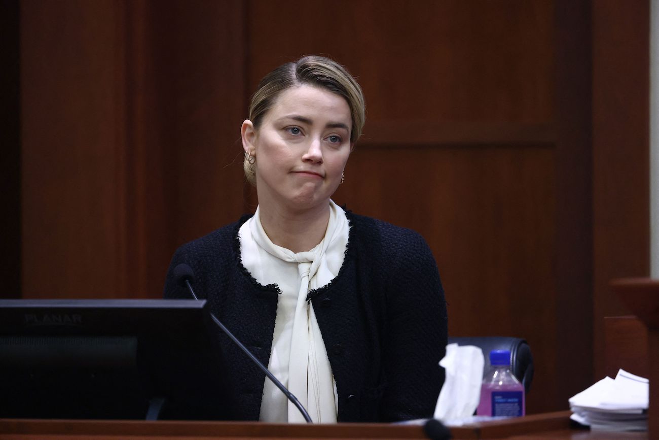 Amber Heard wearing a black-and-white outfit while sitting in court