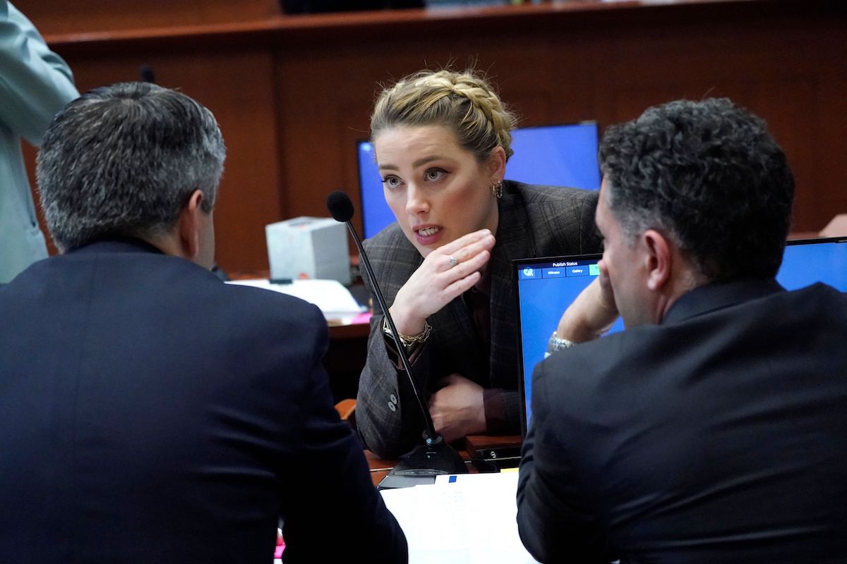 Amber Heard talks to her attorney in the courtroom during a break