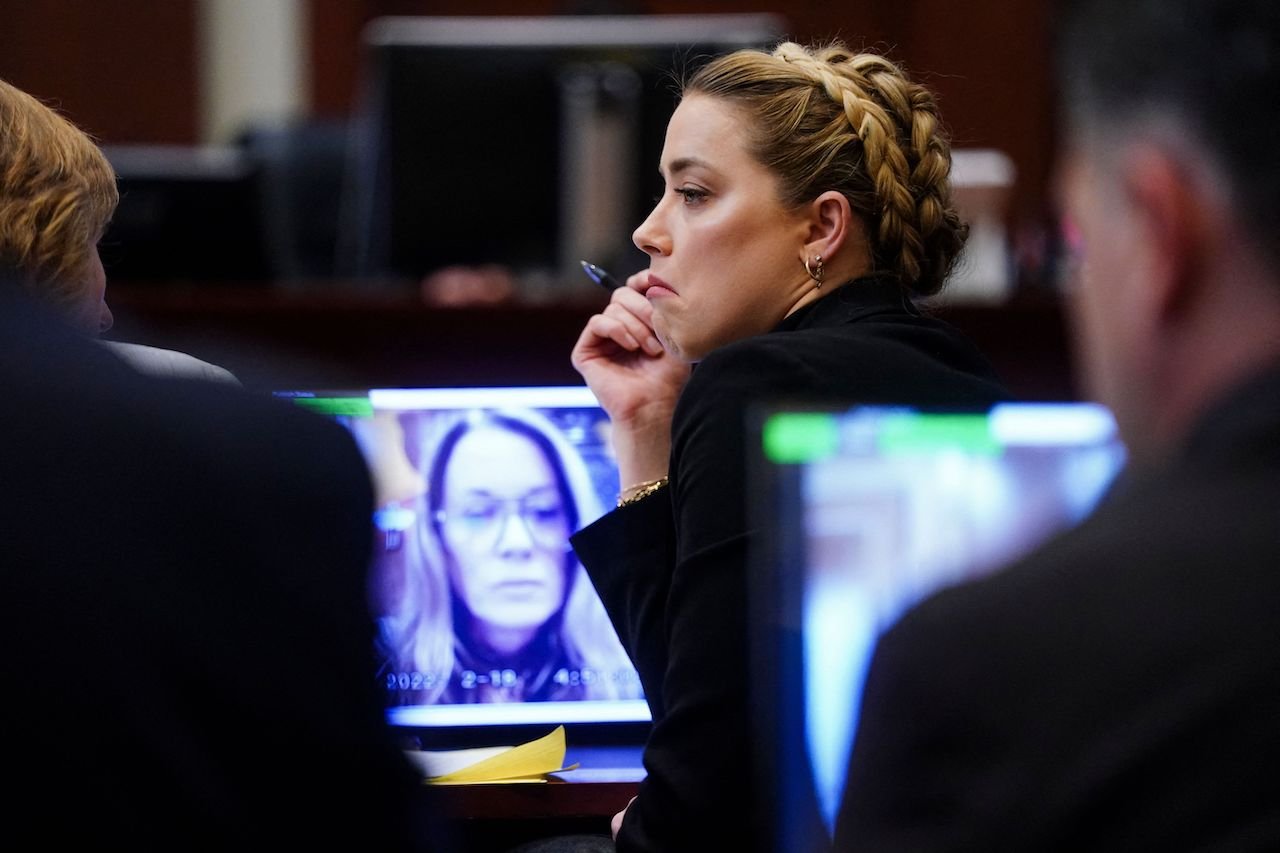 Amber watches as her former assistant's deposition plays in court