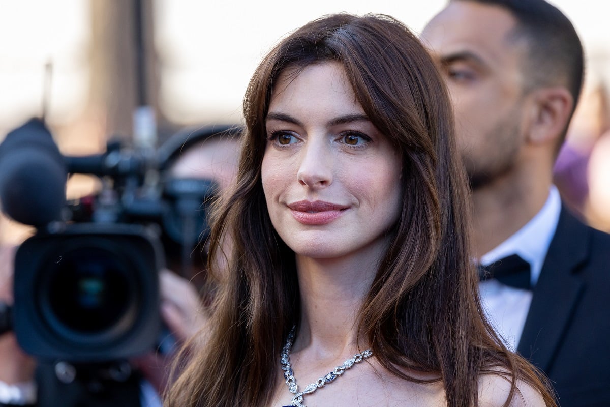 Anne Hathaway smiling while wearing a white dress.