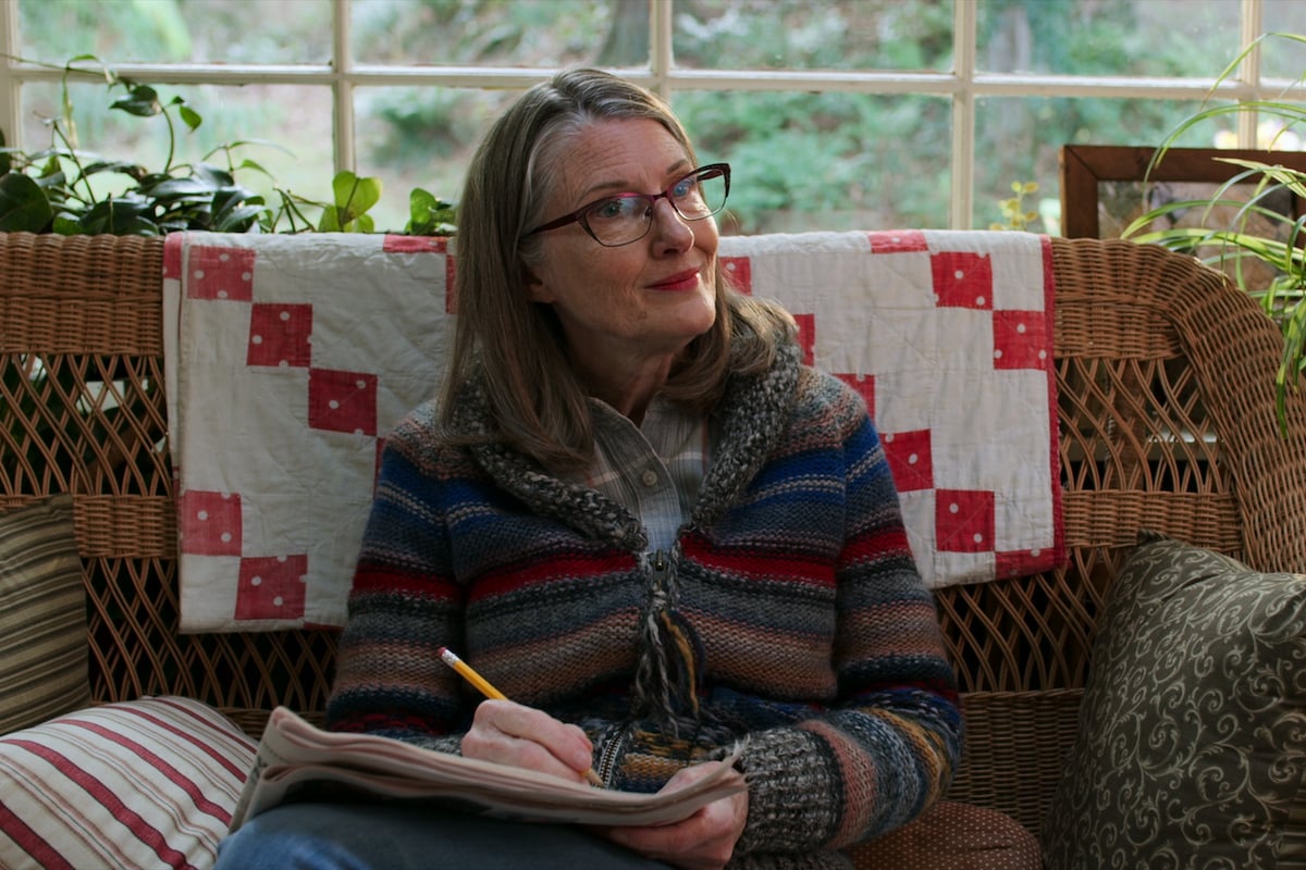 Annette O'Toole as Hope McCrea smiling and sitting on the couch in 'Virgin River'