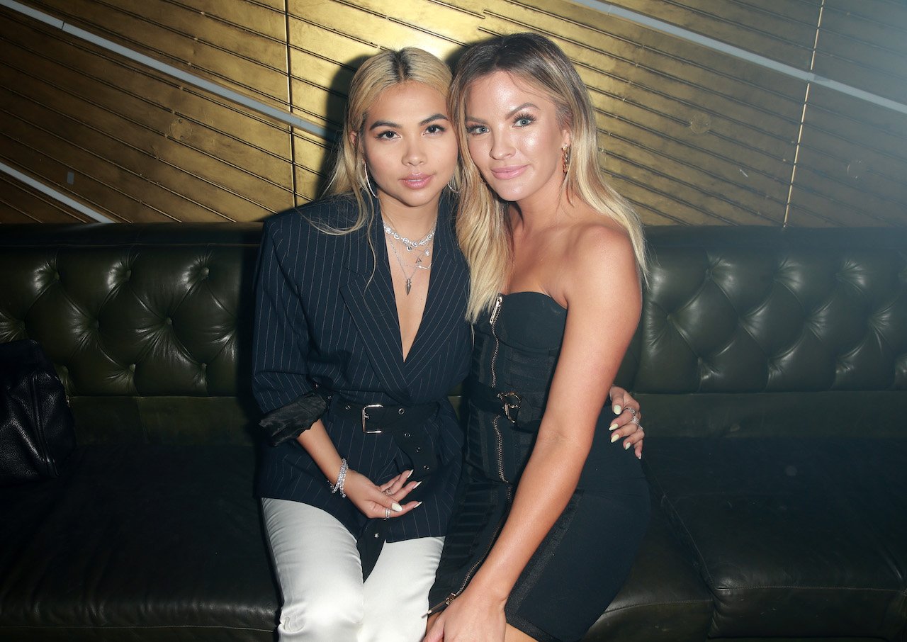 Hayley Kiyoko and Becca Tilley pose together on a couch.
