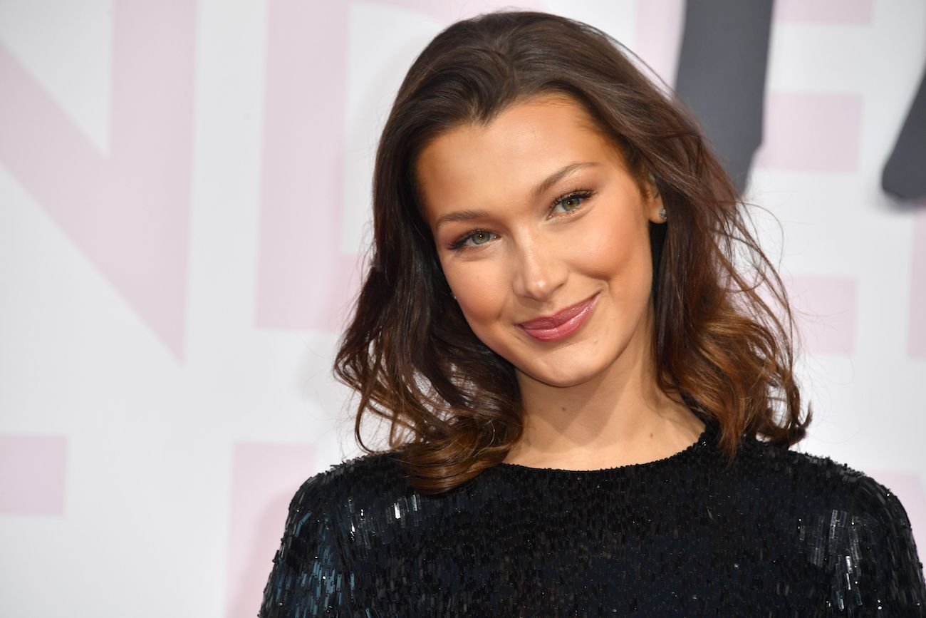 Bella Hadid with her hair down and smiling while tilting her head to the right side of the photo