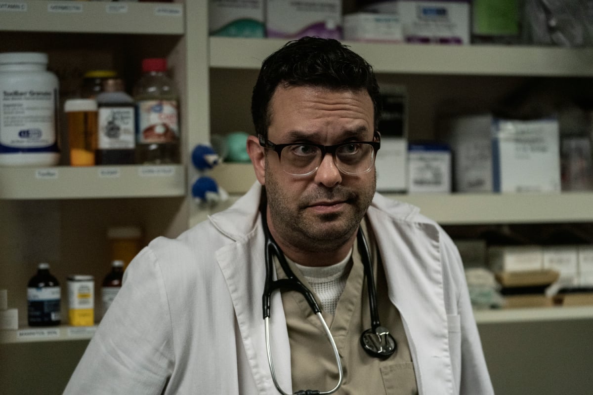 Joe DeRosa as Dr. Caldera in Better Call Saul Season 6. The doctor wears a lab coat and a stethoscope around his neck. 