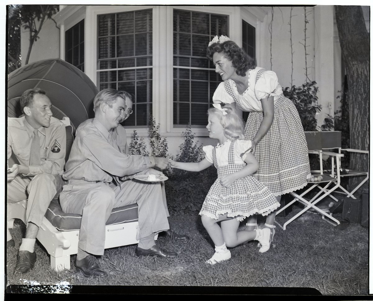 At her home in Brentwood, California, charming movie actress Joan Crawford introduces her adopted daughter, Christina to guests during a party for servicemen