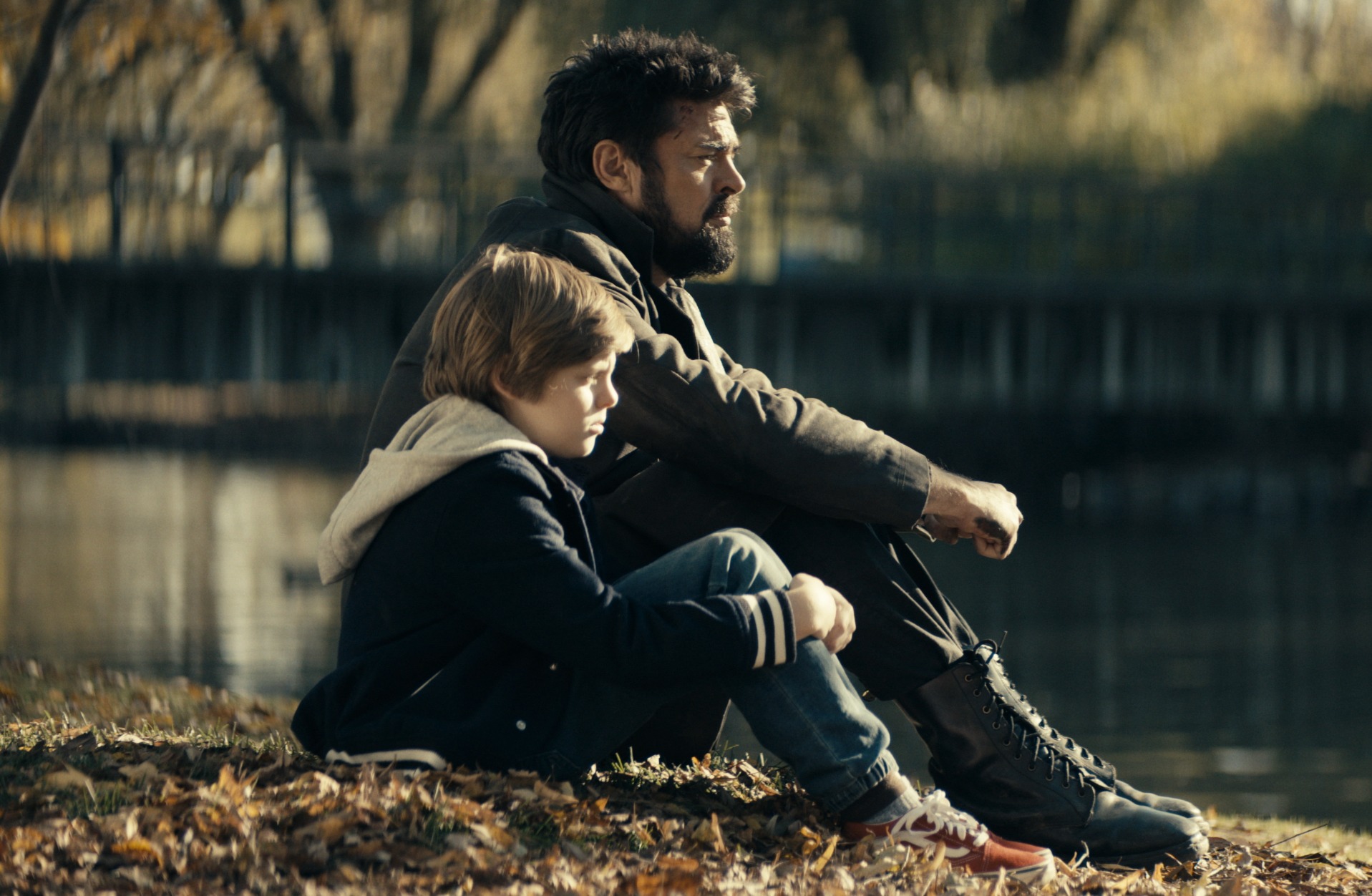 Cameron Crovetti and Karl Urban in 'The Boys' Season 2, which raises questions heading into season 3. The two are sitting next to one another on the grass and looking out at something.