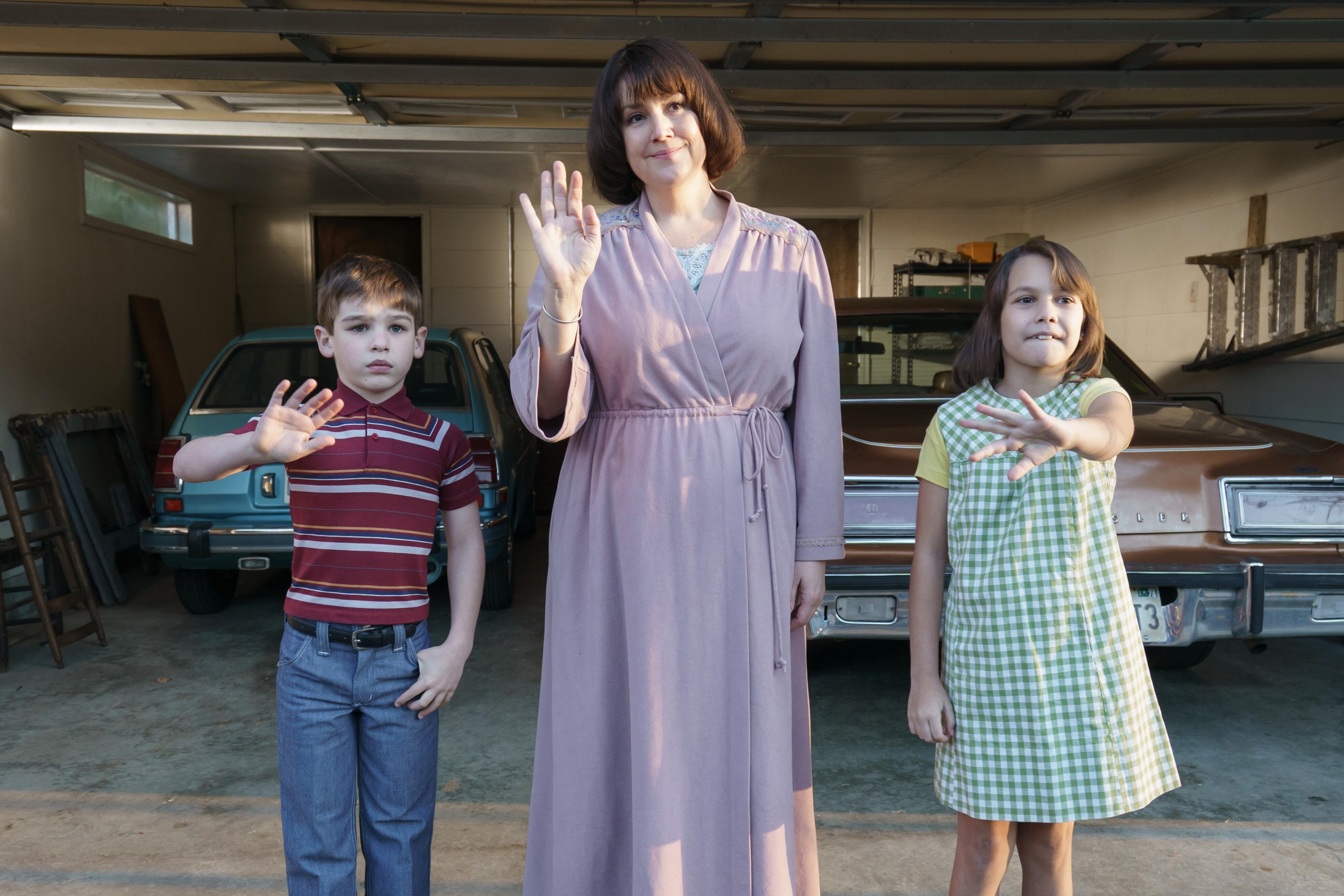 'Candy' cast members Hudson Hughes and Antonella Rose acting as Betty Gore's children standing on either side of Melanie Lynskey waving
