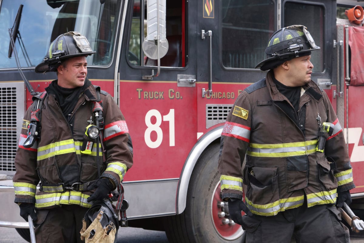 Taylor Kinney as Kelly Severide and Joe Minoso as Joe Cruz in Chicago Fire Season 1. The men stand outside a fire truck.