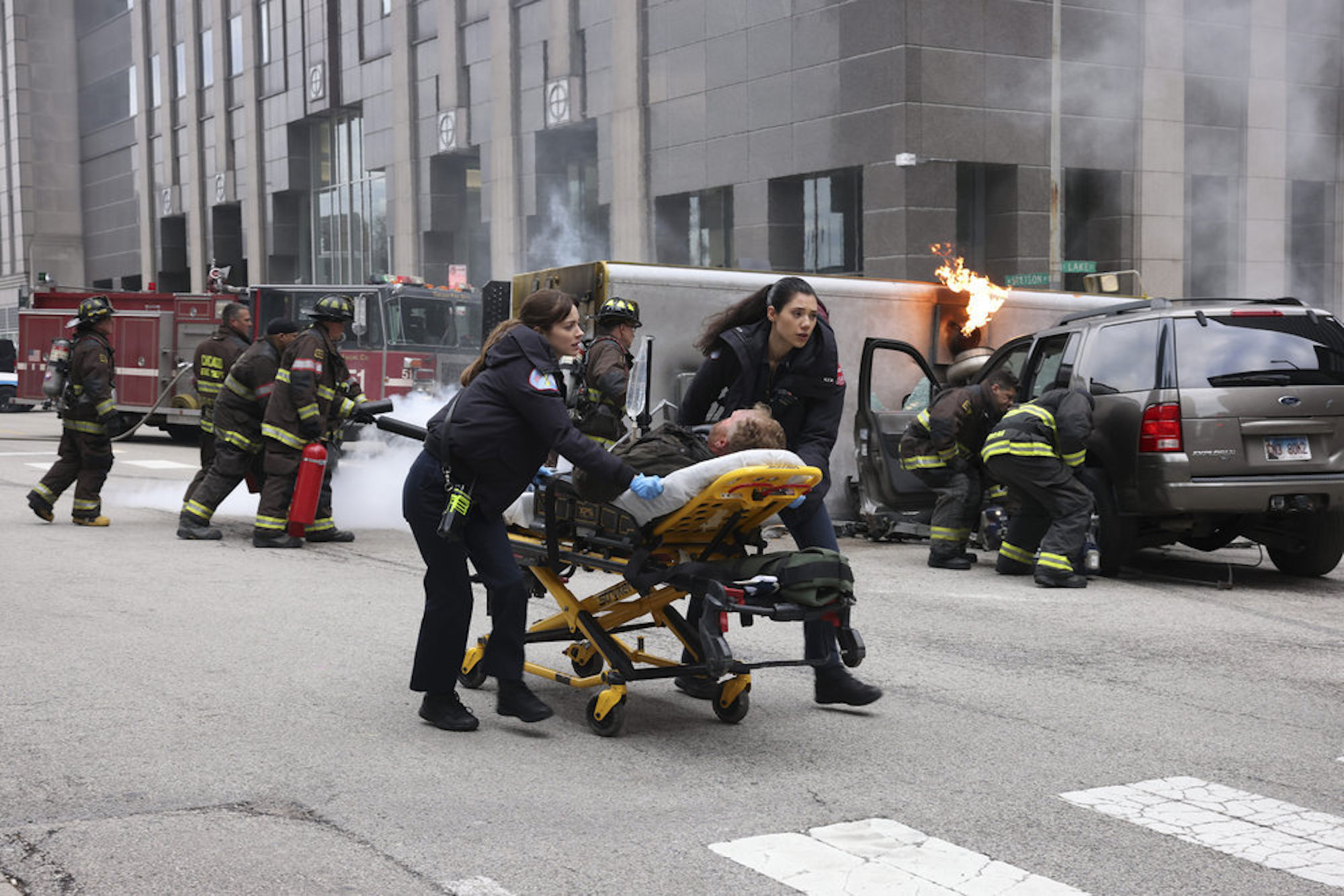 Emma Jacobs and Violet Mikami wheeling away someone in a stretcher on the street in 'Chicago Fire' Season 10 Episode 21