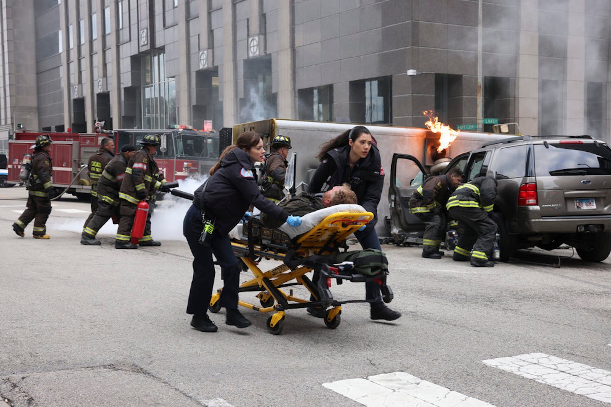 Emma Jacobs and Violet Mikami wheeling away someone in a stretcher on the street in 'Chicago Fire' Season 10 Episode 21