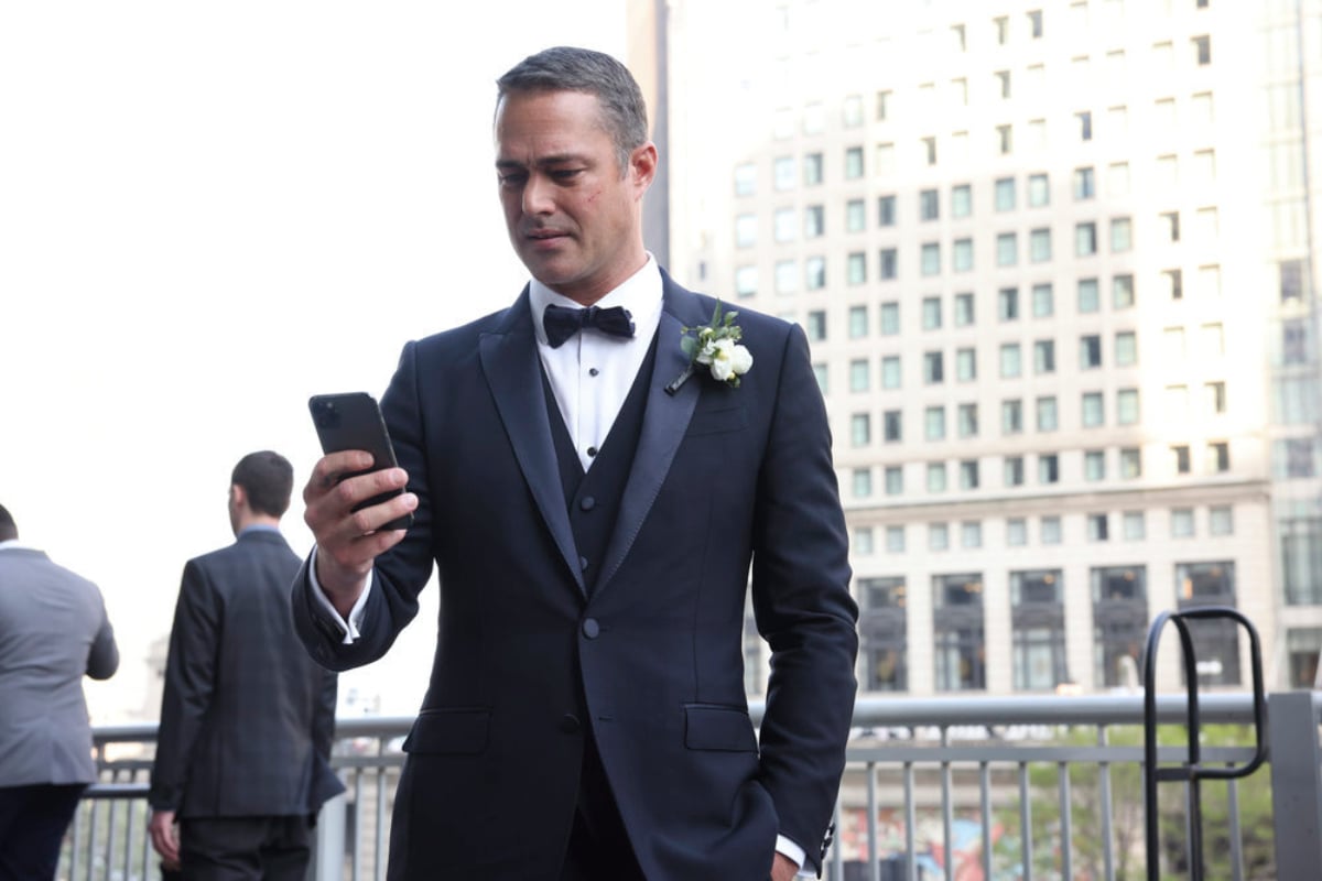 Chicago Fire Season 10 Finale Taylor Kinney as Kelly Severide in a tuxedo looking at his phone