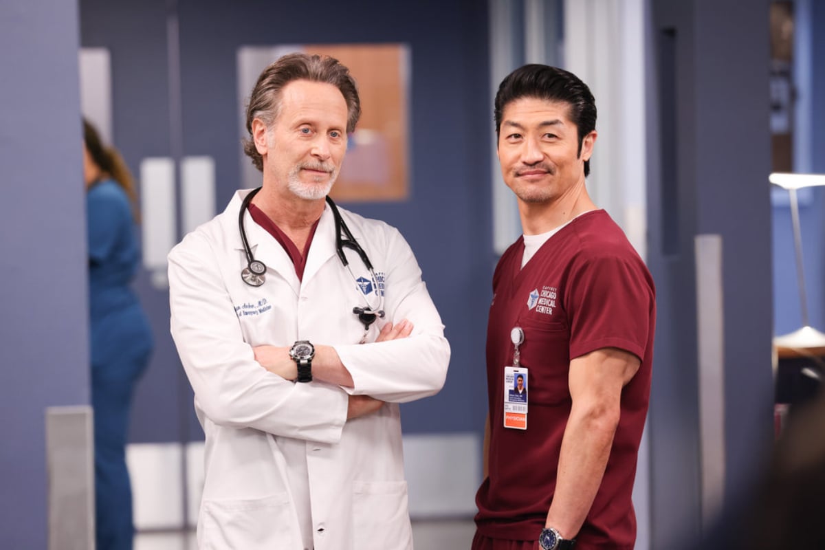 Dr. Dean Archer and Dr. Ethan Choi in the Chicago Med Season 7 finale. Archer and Ethan stand next to each other and smile slightly.