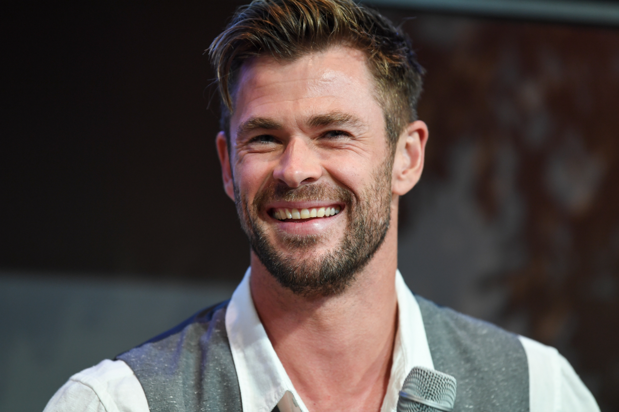 'Thor 4' star Chris Hemsworth. He's wearing a white and gray shirt and laughing.