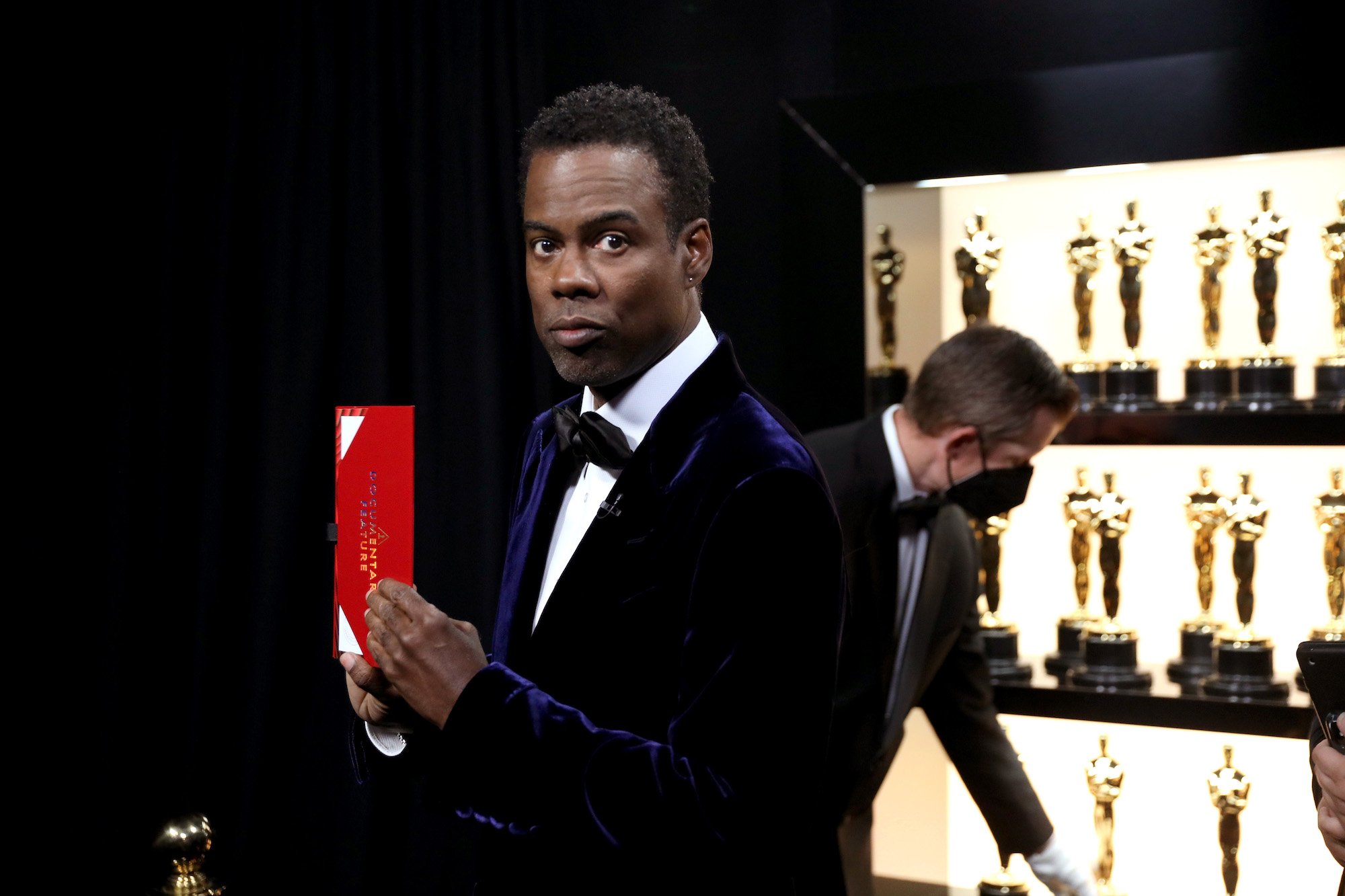 Chris Rock holds the Best Documentary Oscar envelope backstage. Could he host again?