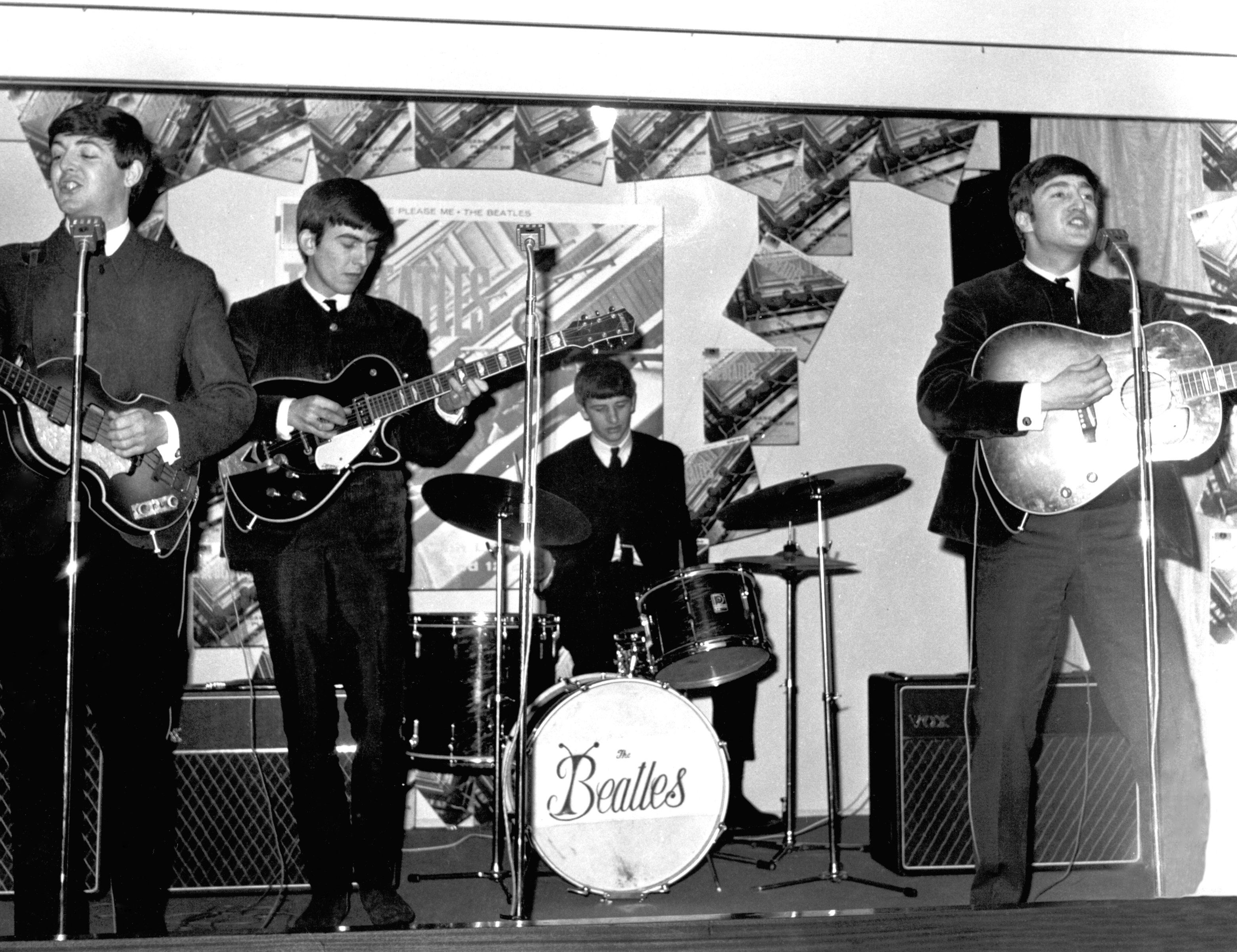 The Beatles' Paul McCartney, George Harrison, Ringo Starr, and John Lennon playing songs on a stage