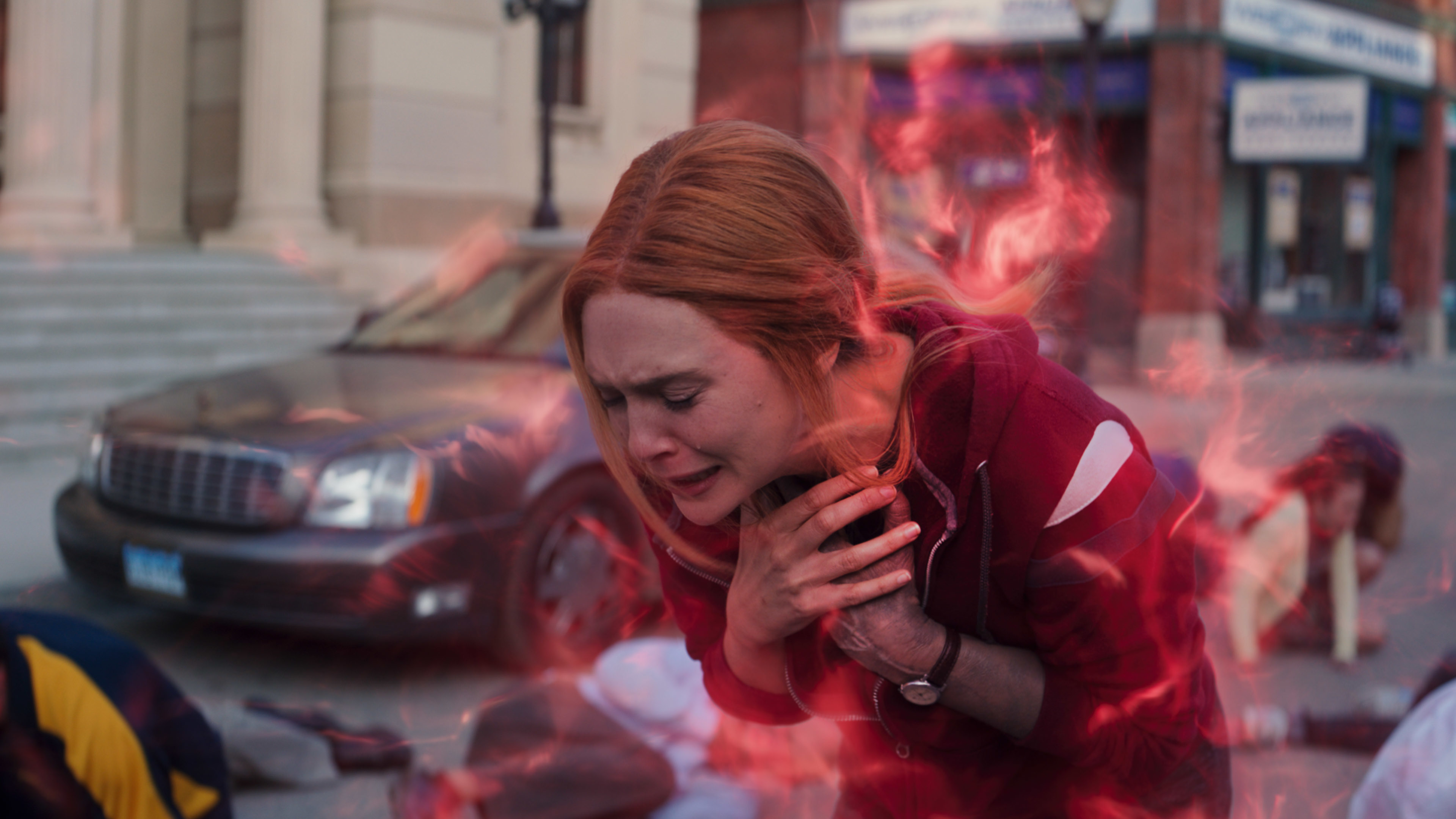Elizabeth Olsen, who plays Scarlet Witch in 'Doctor Strange 2,' wears a red and white hoodie as red magic swirls around her and chokes her.