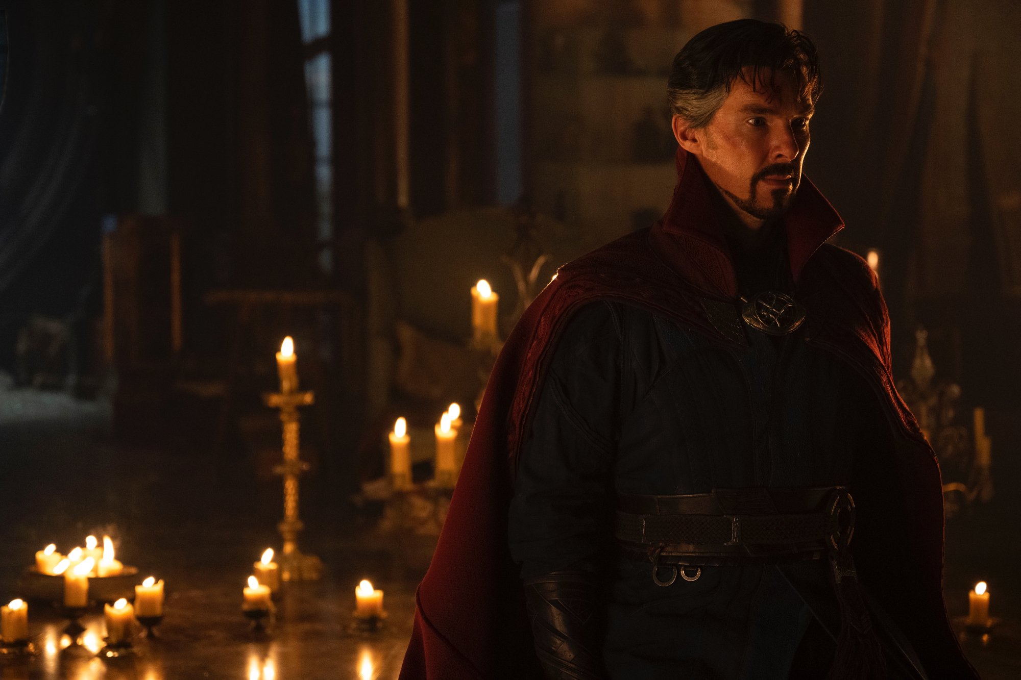 'Doctor Strange in the Multiverse of Madness' Benedict Cumberbatch as Dr. Stephen Strange standing in a dark room full of candles in the background