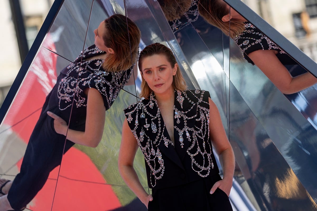 Elizabeth Olsen posing while wearing a black and white dress.