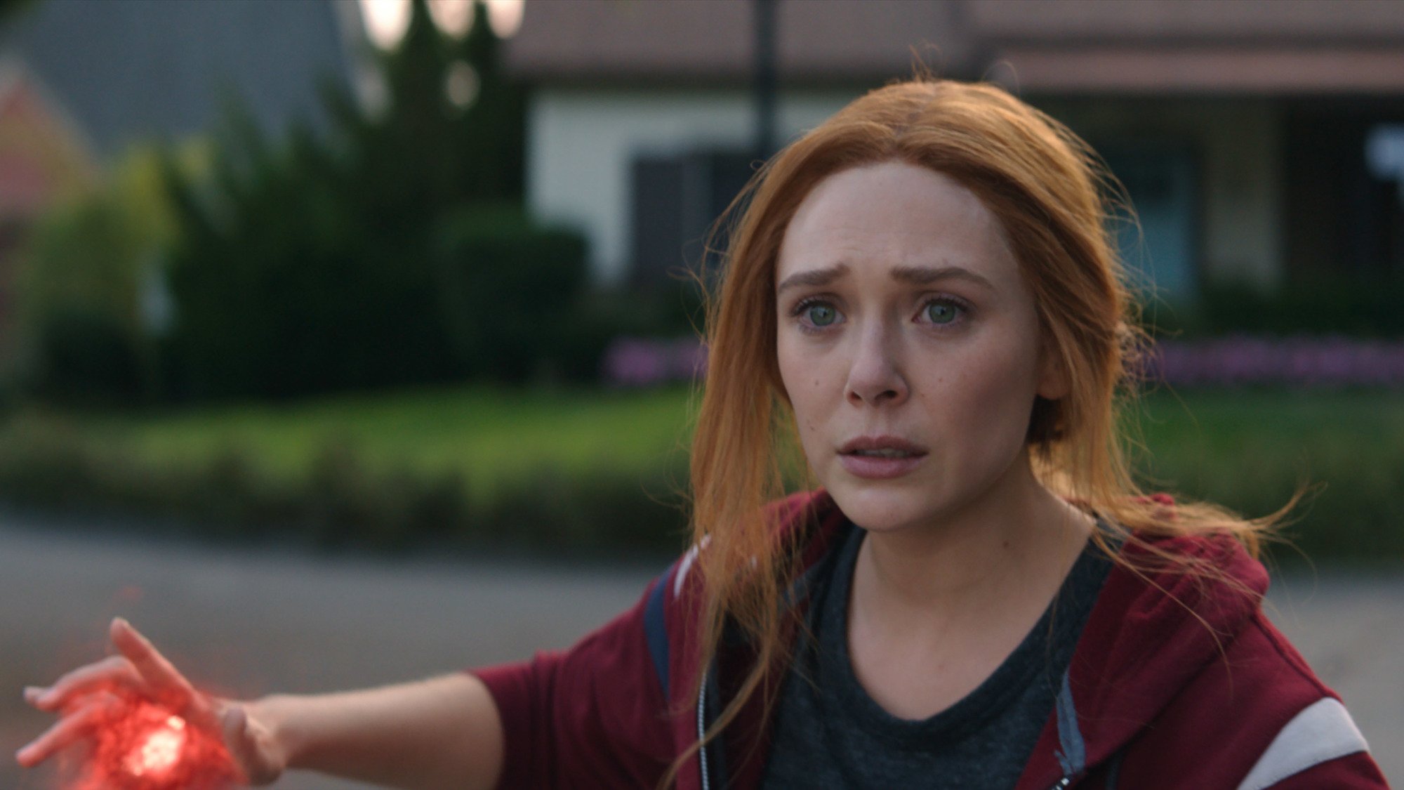 Elizabeth Olsen as Wanda Maximoff in 'WandaVision.' She's wearing a sweatshirt and about to use her powers, but she looks upset about something.