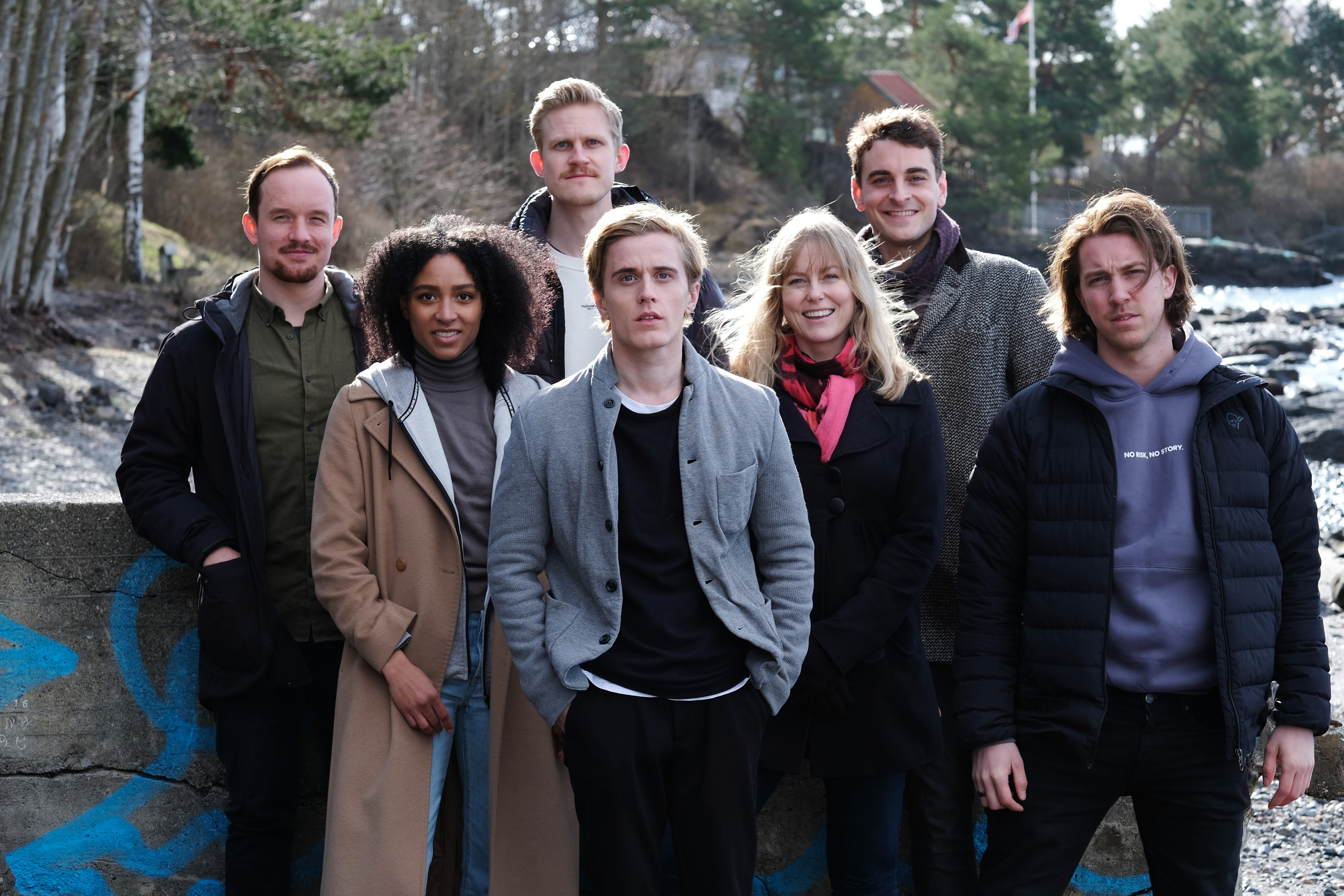 Blasted cast stand outside wearing coats.